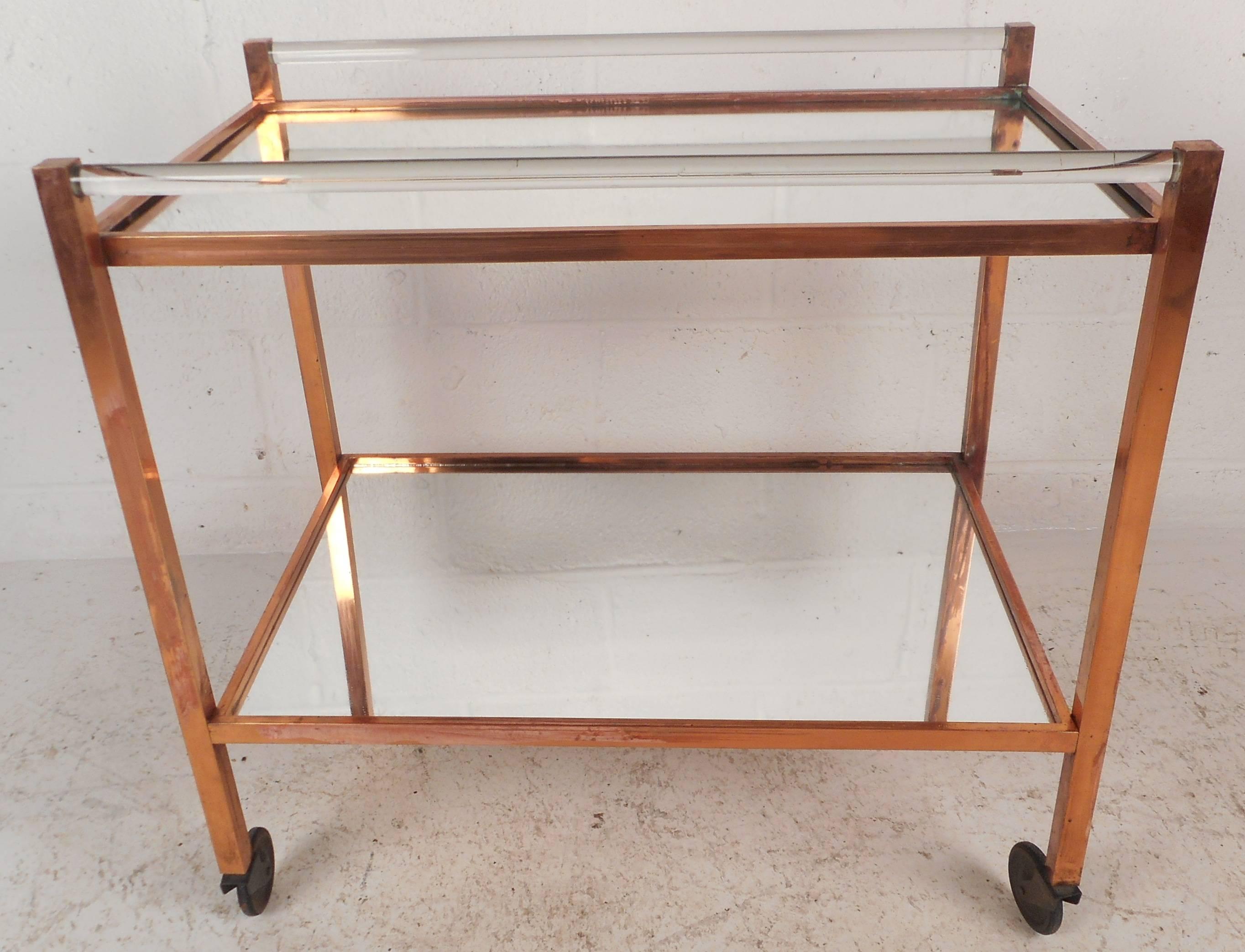 This stunning vintage modern bar cart features a rare combination of copper and Lucite. The stylish design has two mirrored tiers adding to the allure. This unusual piece shows quality construction. This elegant mid-century piece is sure to