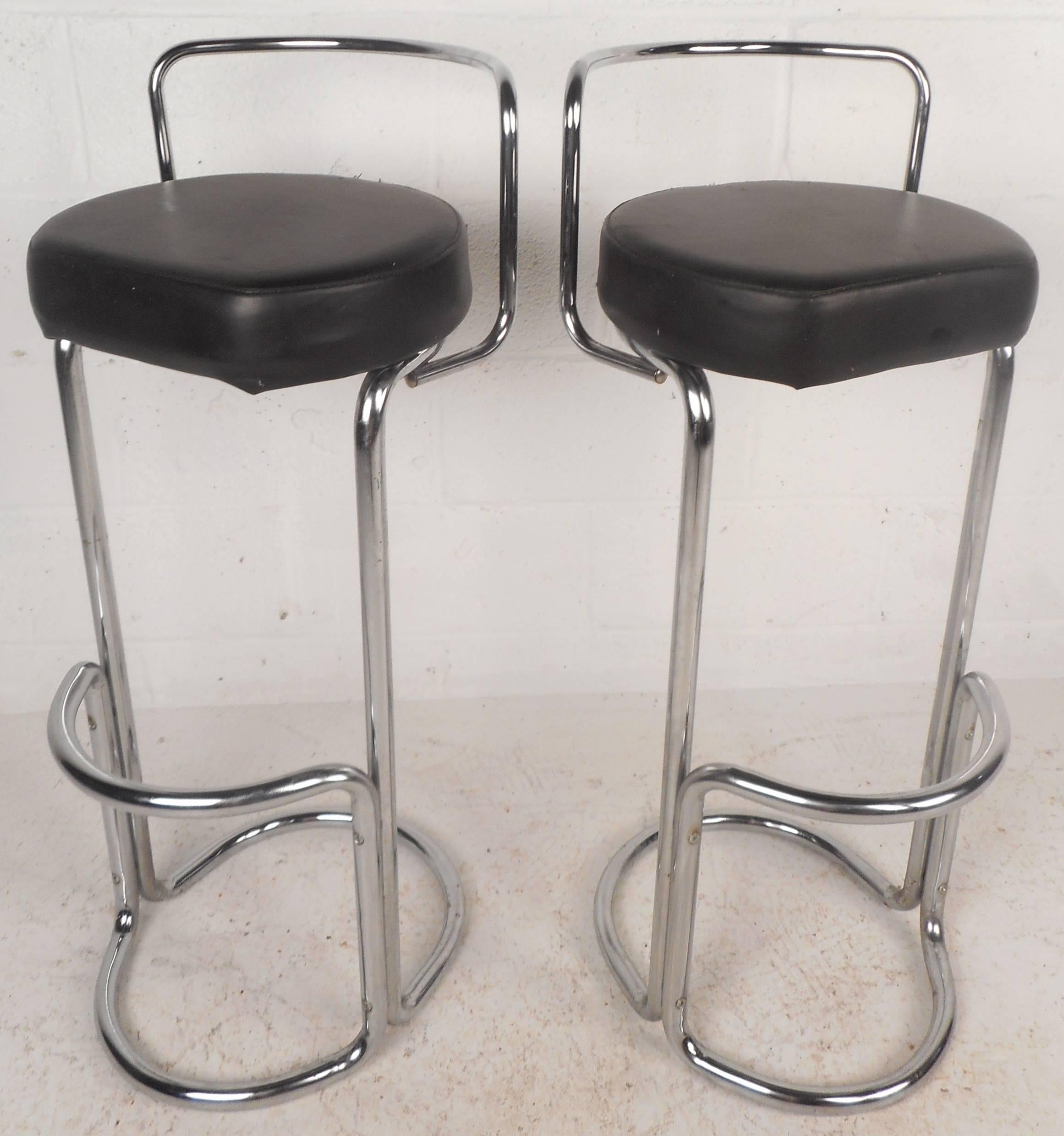 This stunning pair of vintage modern bar stools feature unique sculpted chrome frames with a vinyl seat. Sleek design with a rounded chrome backrest, kick rest, and a sturdy oval base. The stylish bent rod tubular frame ensures comfort and style in