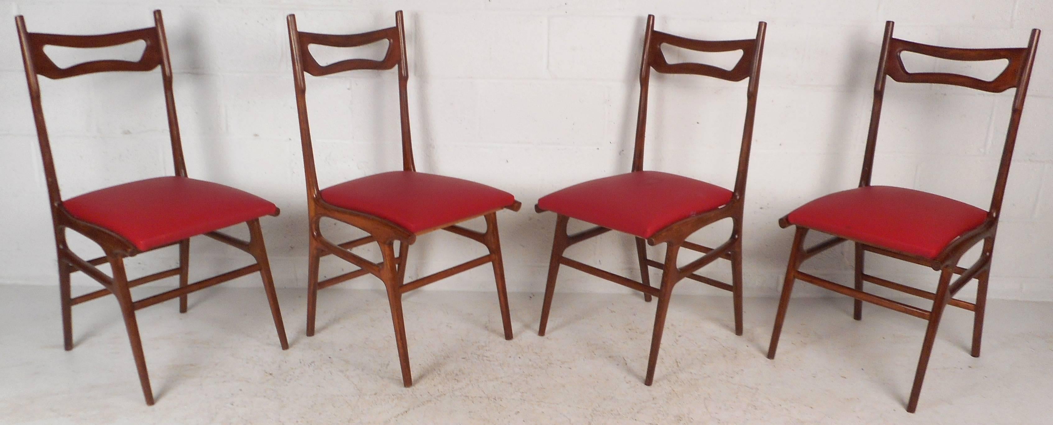 This gorgeous set of four vintage modern Italian dining chairs feature sculpted walnut frames with angled and tapered legs. Unique "Cut-out" design on an unusually high backrest ensures comfortable seating without sacrificing style.