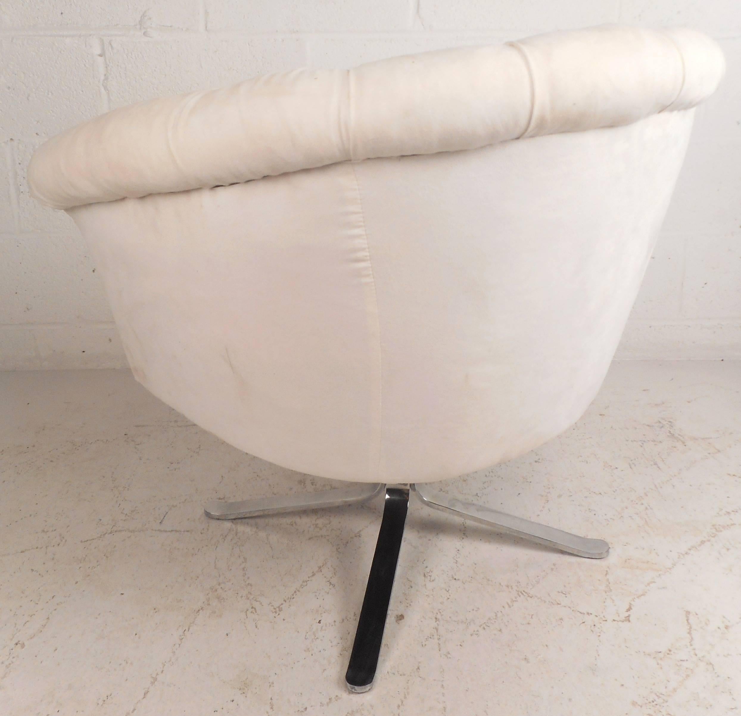 Beautiful vintage modern lounge chair features thick padded seating with plush velvet upholstery. This luxury style barrel back chair has an unusual chrome swivel base with splayed legs. Sleek design with tufted upholstery and winged arm rests