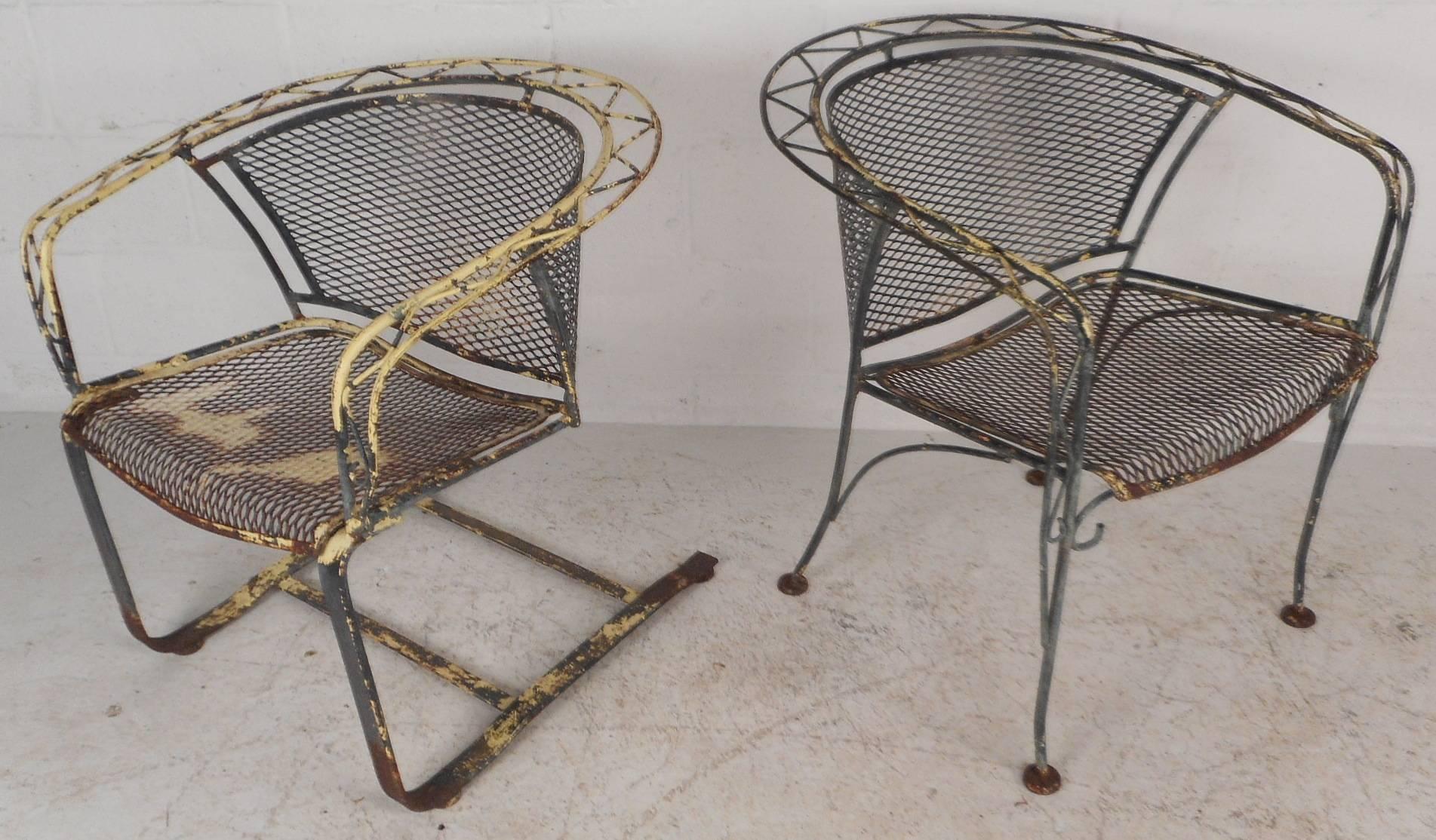 This gorgeous Mid-Century Modern patio set is made entirely of wrought iron and features a sculpted frame. Unique design with scroll detail, barrel back rests, and angled legs. One chair has sled base while the other sits on four sturdy legs.