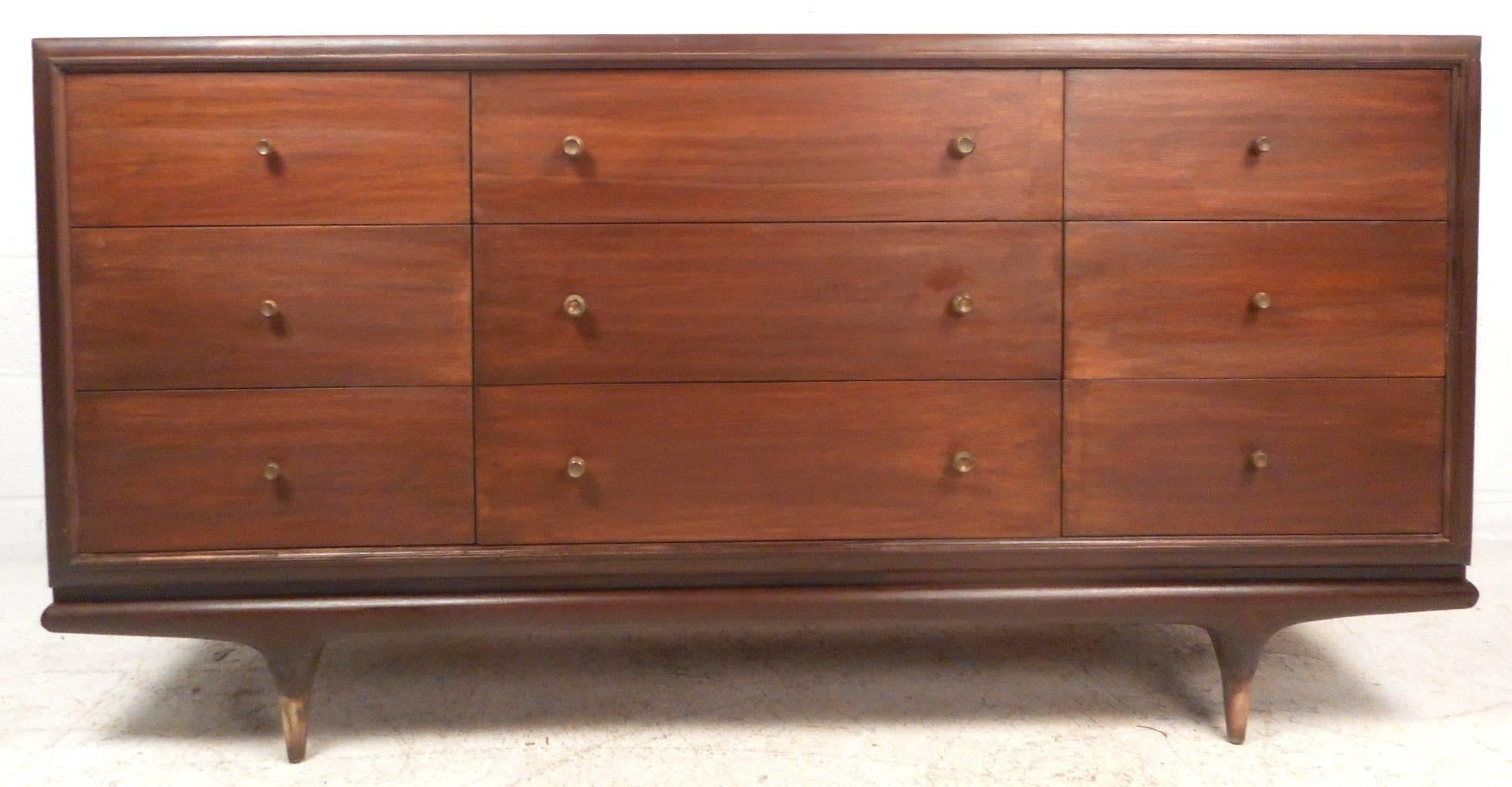This gorgeous vintage modern bedroom set features a highboy dresser with five large drawers and a low dresser with nine drawers. Sleek design offers ample room for storage without sacrificing style. Unique round brass pulls on each drawer and