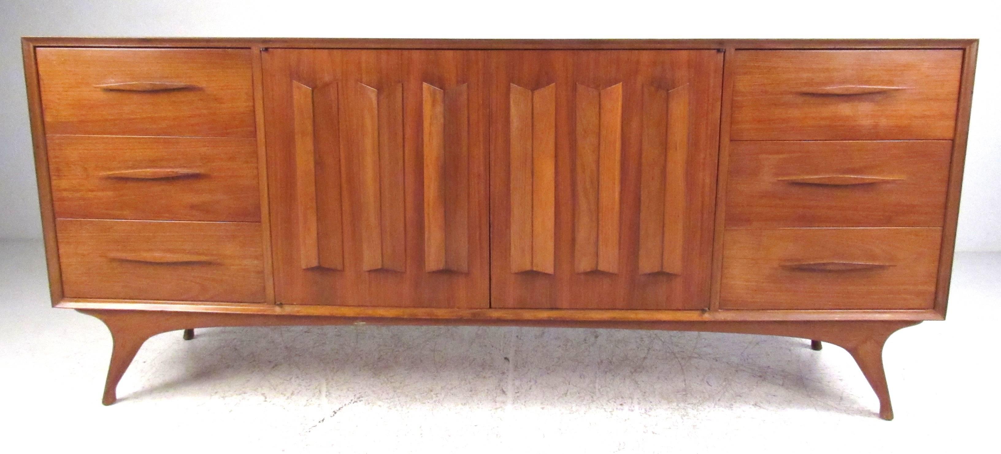 Stylish Mid-Century dresser/credenza with dimensional double doors flanked by storage drawers on each side with carved pulls. Please confirm item location (NY or NJ) with dealer.