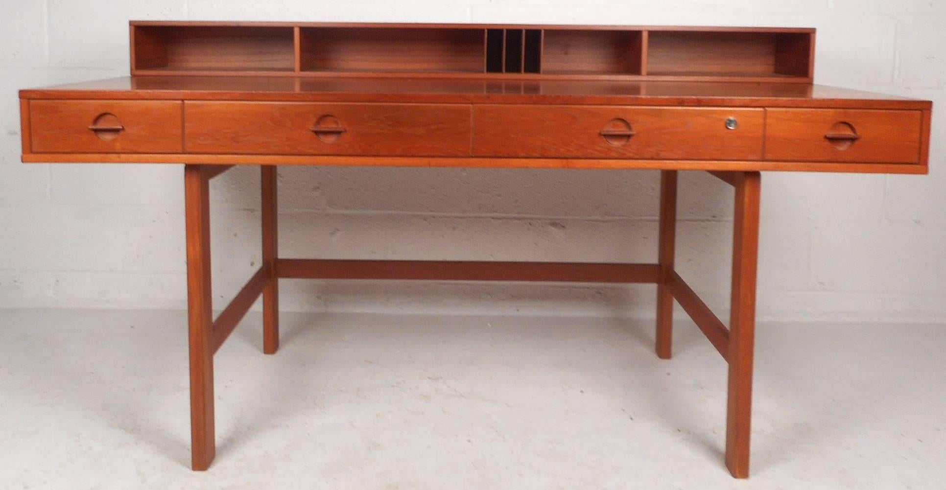Stunning vintage modern desk features a unique top that flips down and adds plenty of work space. Sleek and functional design with four large drawers and numerous compartments on the top. Quality construction has a finished back with additional