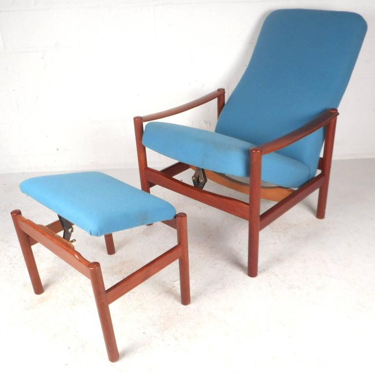 Beautiful vintage modern lounge chair and ottoman with sculpted teak frames and elegant plush blue upholstery. Sleek design offers the ability for both pieces to recline for optimal comfort. Unique high backrest, cylindrical legs, thick padded