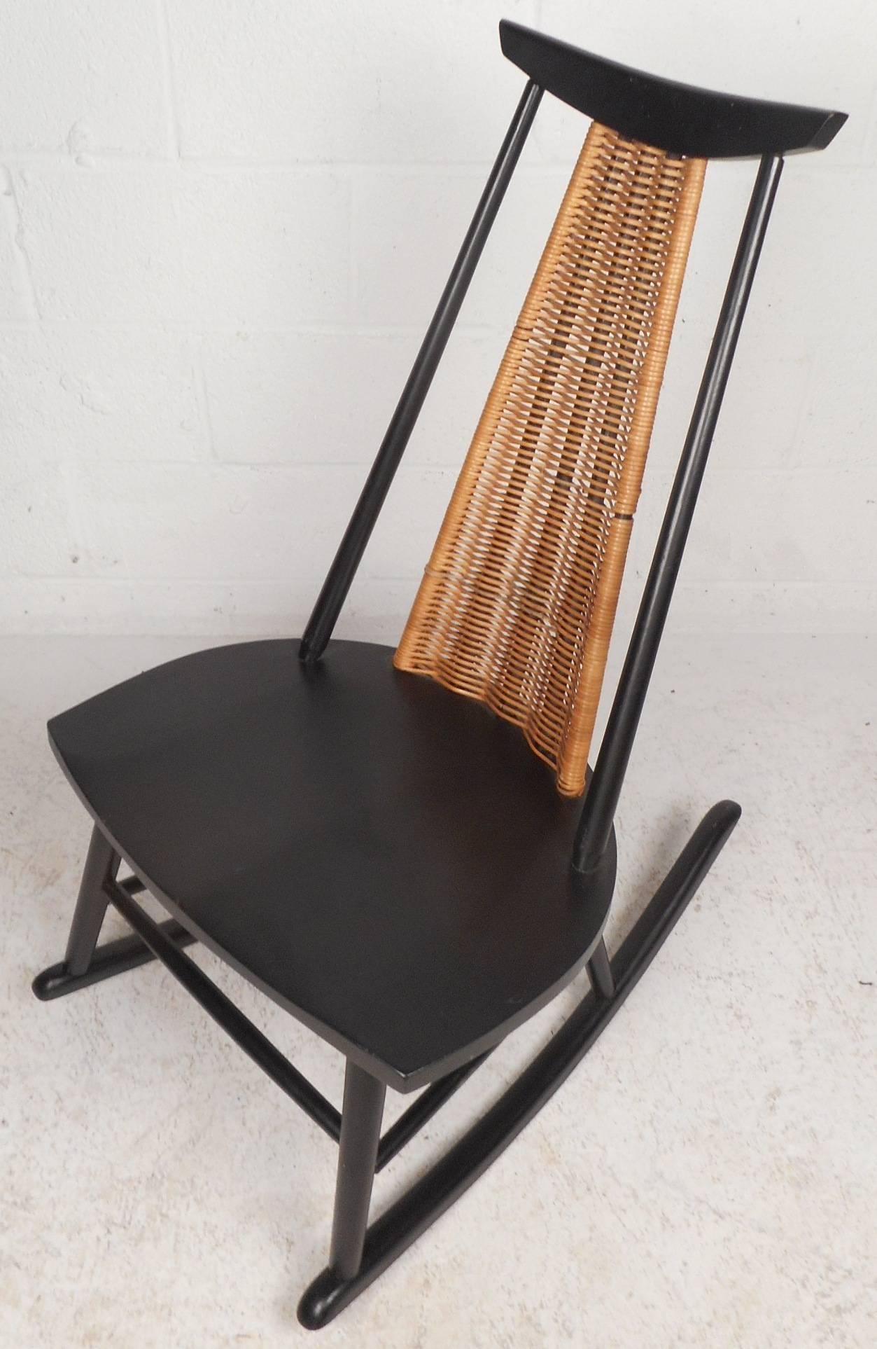 This gorgeous vintage modern rocking chair features an ebonized finish and a unique woven backrest. Sleek design with perfectly contoured seating for optimal comfort and a trapezoid backrest with spindle sides. The sculpted head rest and angled feet