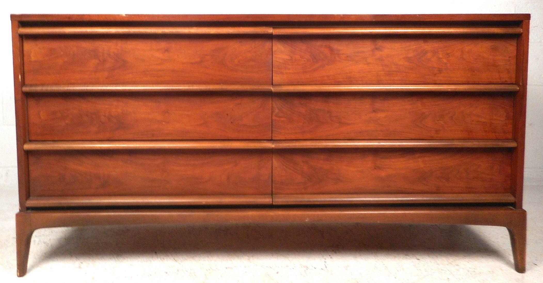 This stunning vintage modern set features eleven hefty drawers combined providing plenty of room for storage. Beautiful walnut wood grain runs different directions on the top edges displaying quality craftsmanship. The unique sculpted base has four