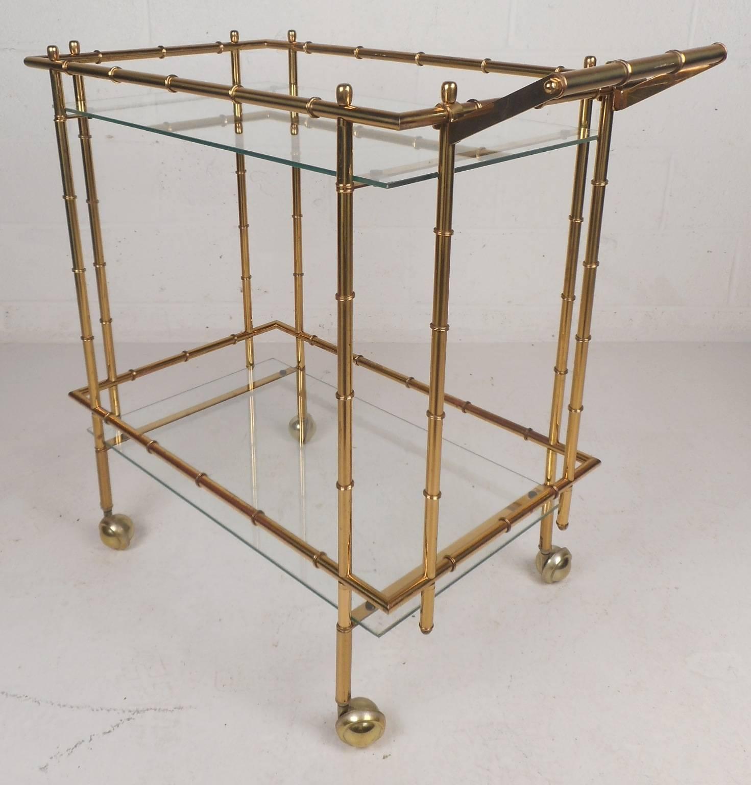 Elegant vintage modern serving car features a faux bamboo brass frame on castors. Unique design with two rectangular glass shelves for placing items. This beautiful Mid-Century piece makes the perfect addition to any home, business, or office.