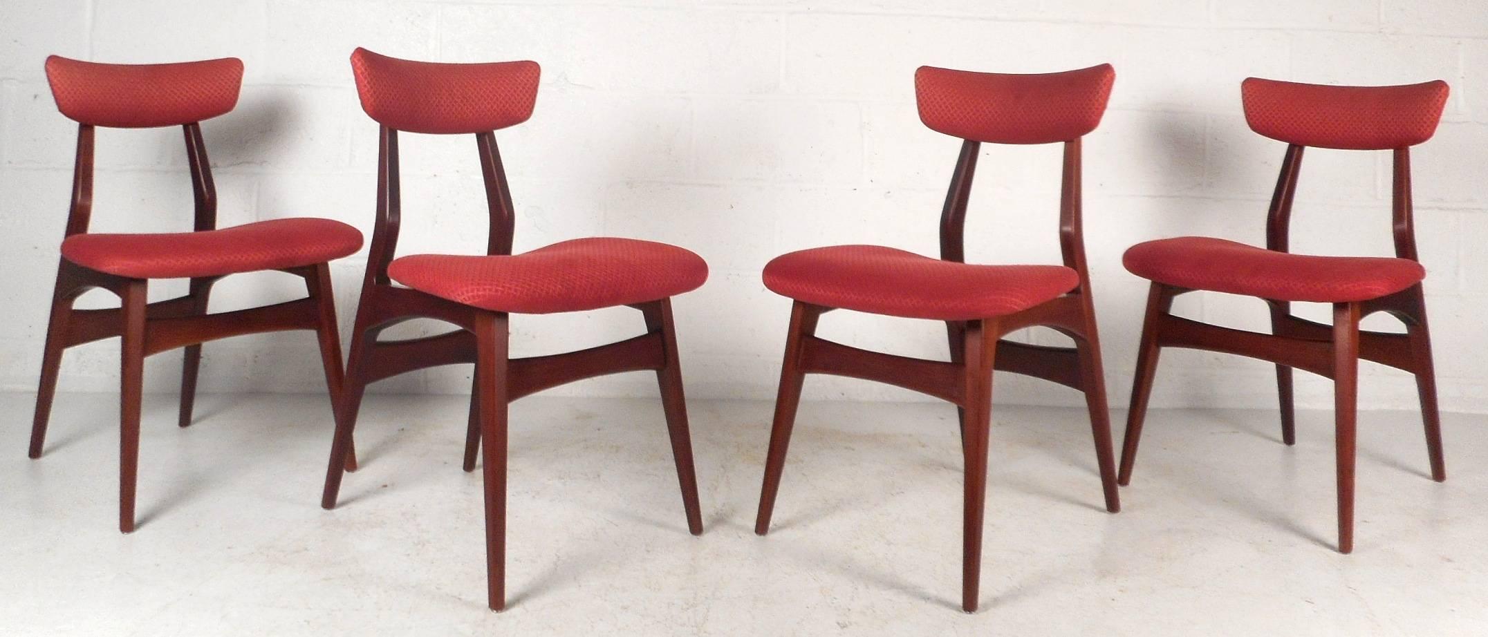 This exquisite set of four vintage modern dining chairs feature an unusual sculpted walnut frame with angled and tapered legs. Sleek design with shapely floating back rests and elegant plush red upholstery. Quality craftsmanship by George Nelson has