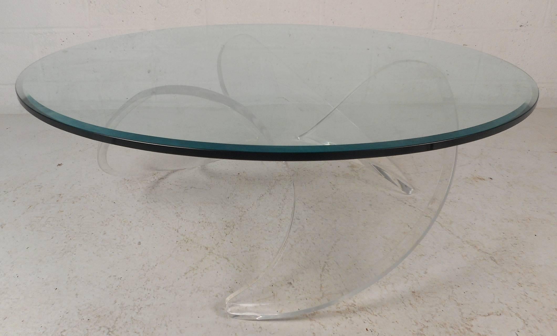 Gorgeous vintage modern coffee table with an unusual thick Lucite propeller shaped base and a round glass top. Sleek design features bevelled edges on the base and the thick glass top. This one of a kind stylish and sturdy piece makes the perfect