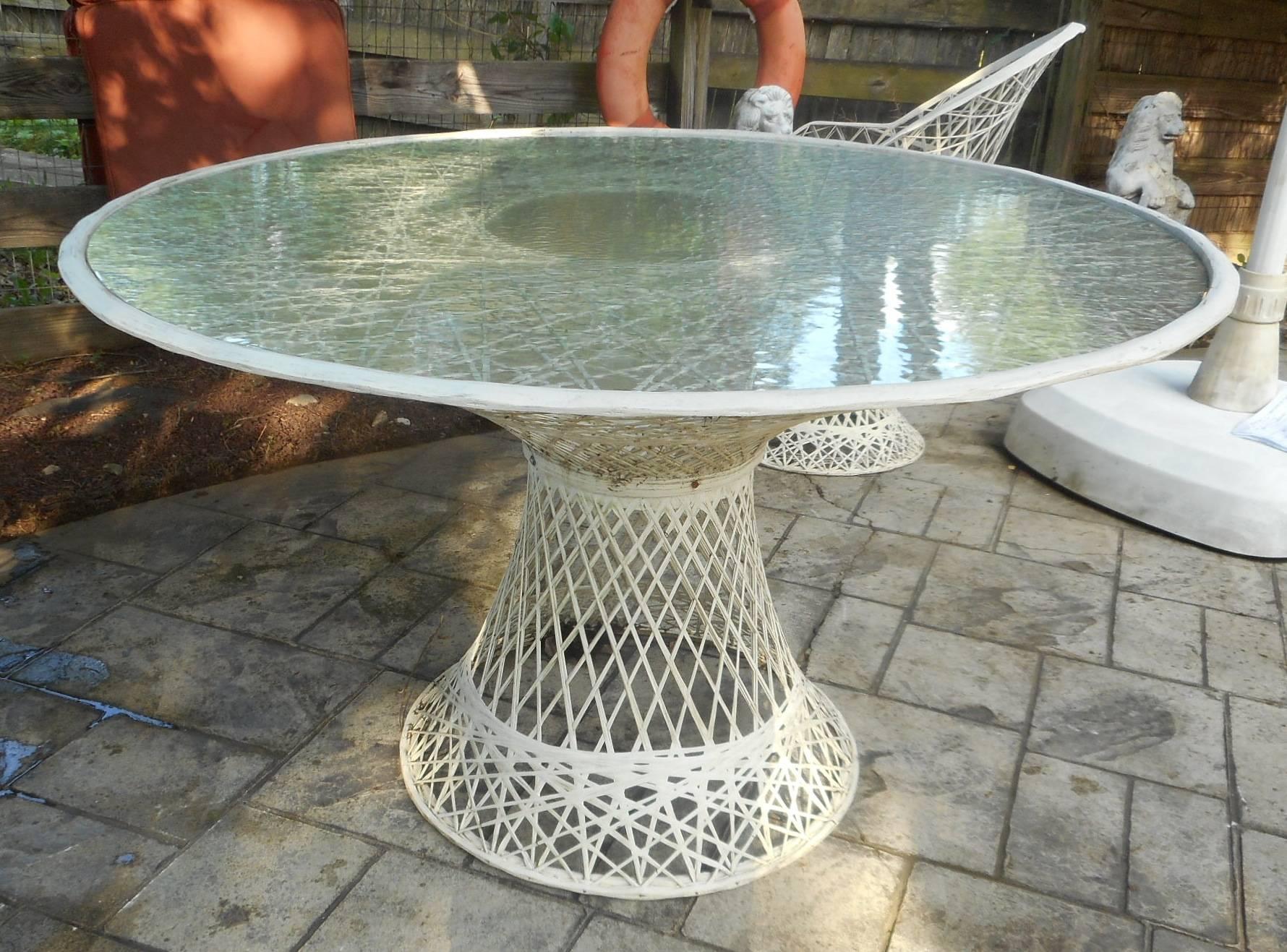 This beautiful vintage modern patio set includes four chairs and a round glass top dining table. Unique design made of woven fiberglass with tulip shaped bases. Extremely comfortable dining chairs with angled back rests and a matching table make the