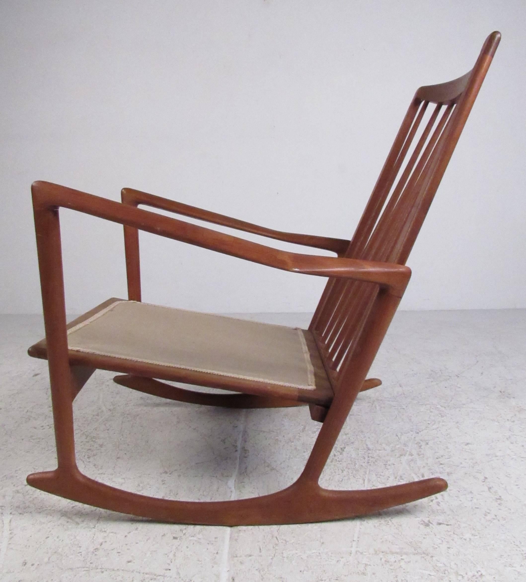 Mid-Century Scandinavian modern solid teak rocking chair designed by Ib Kofod Larsen and produced by Selig. Sculptural profile with high spindle back, this Classic chair retains its original manufacturers label. Please confirm item location (NY or