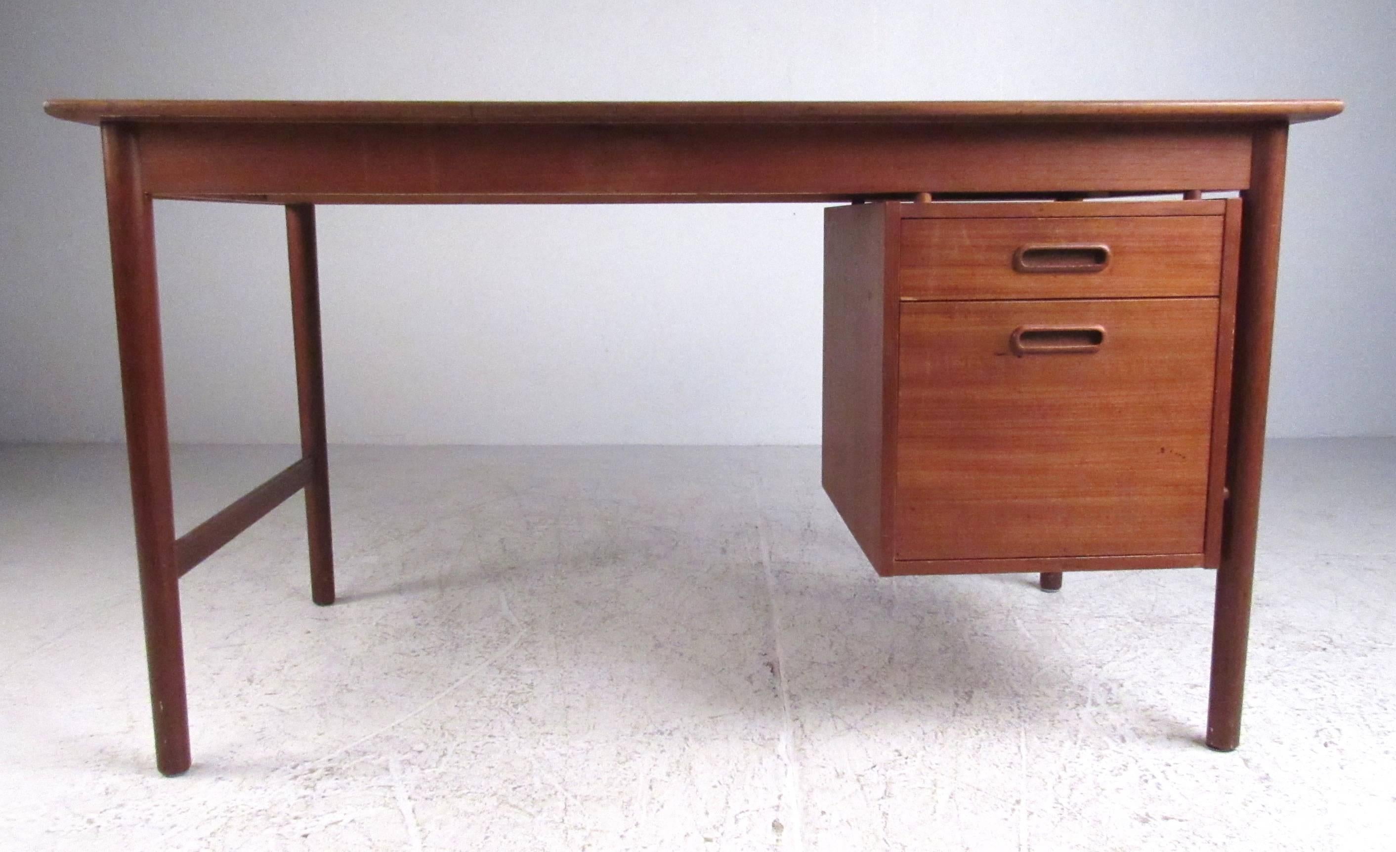 Danish Modern teak writing desk by Folke Ohlsson for DUX. The floating cabinet design contains two drawers with recessed pulls, with the desktop having a raised back lip and tapered front edge of solid teak. Branded makers mark and model number on