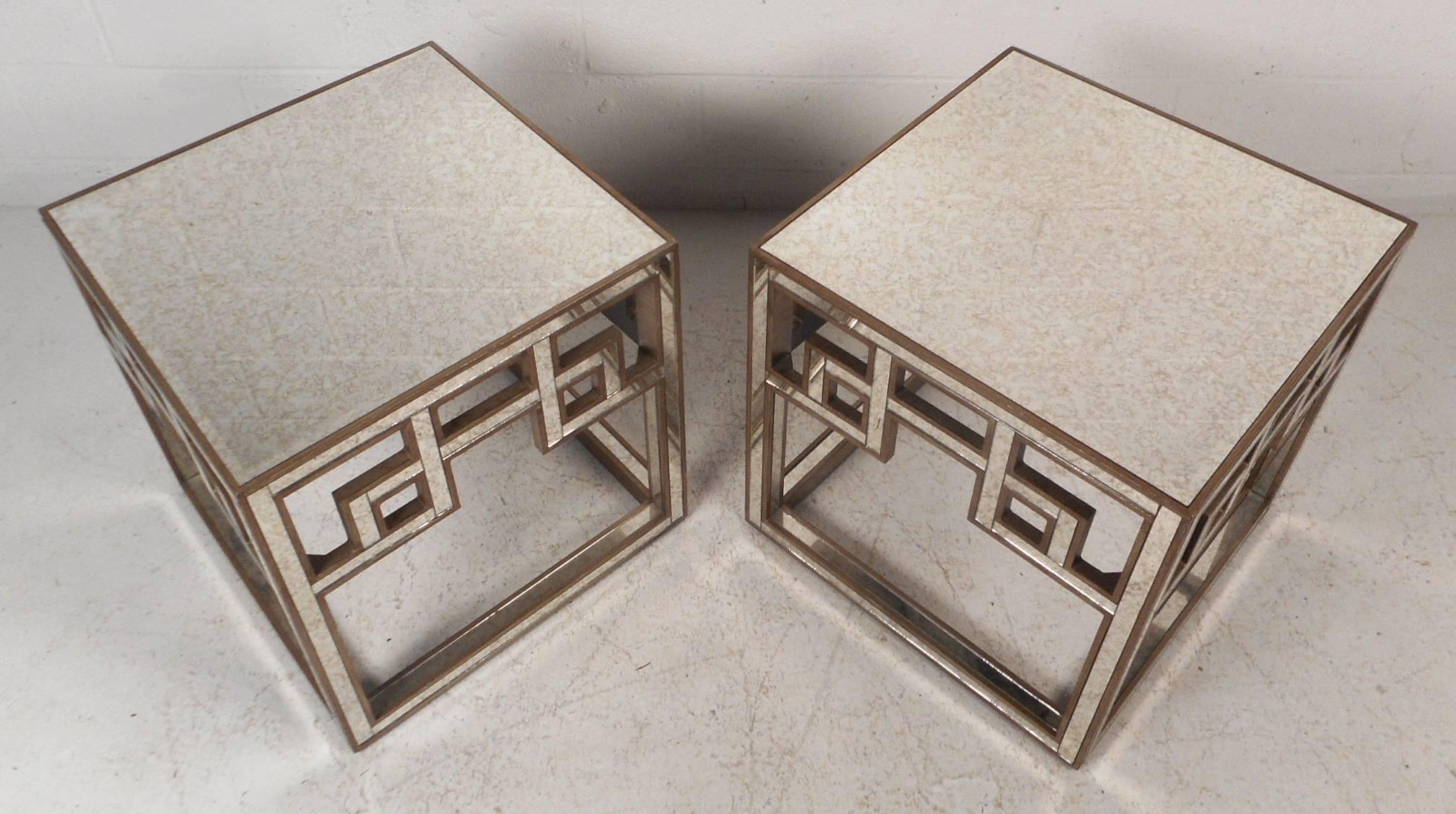 This stunning pair of vintage modern square end tables feature a mirrored top and sides with gold brushed trim. This elegant Hollywood Regency style pair have unique cut-out square and rectangular designs. Sleek antique style mirrored glass with