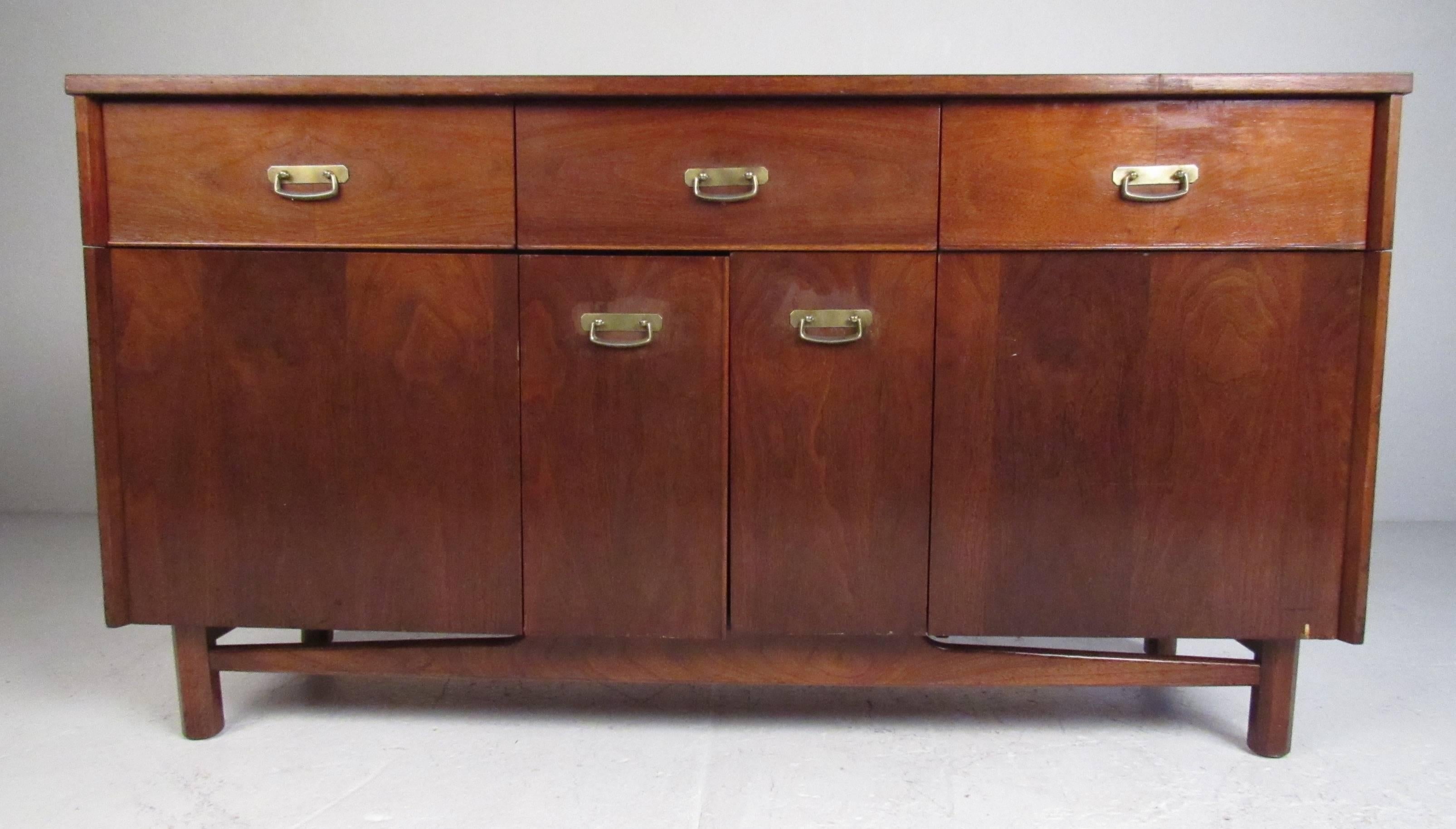 Mid-Century Modern walnut credenza/buffet with durable laminate top, three top drawers and two bi-fold doors with shelf storage. A beautiful example of the high quality work from Young Manufacturing Company, built in Kentucky. Please confirm item