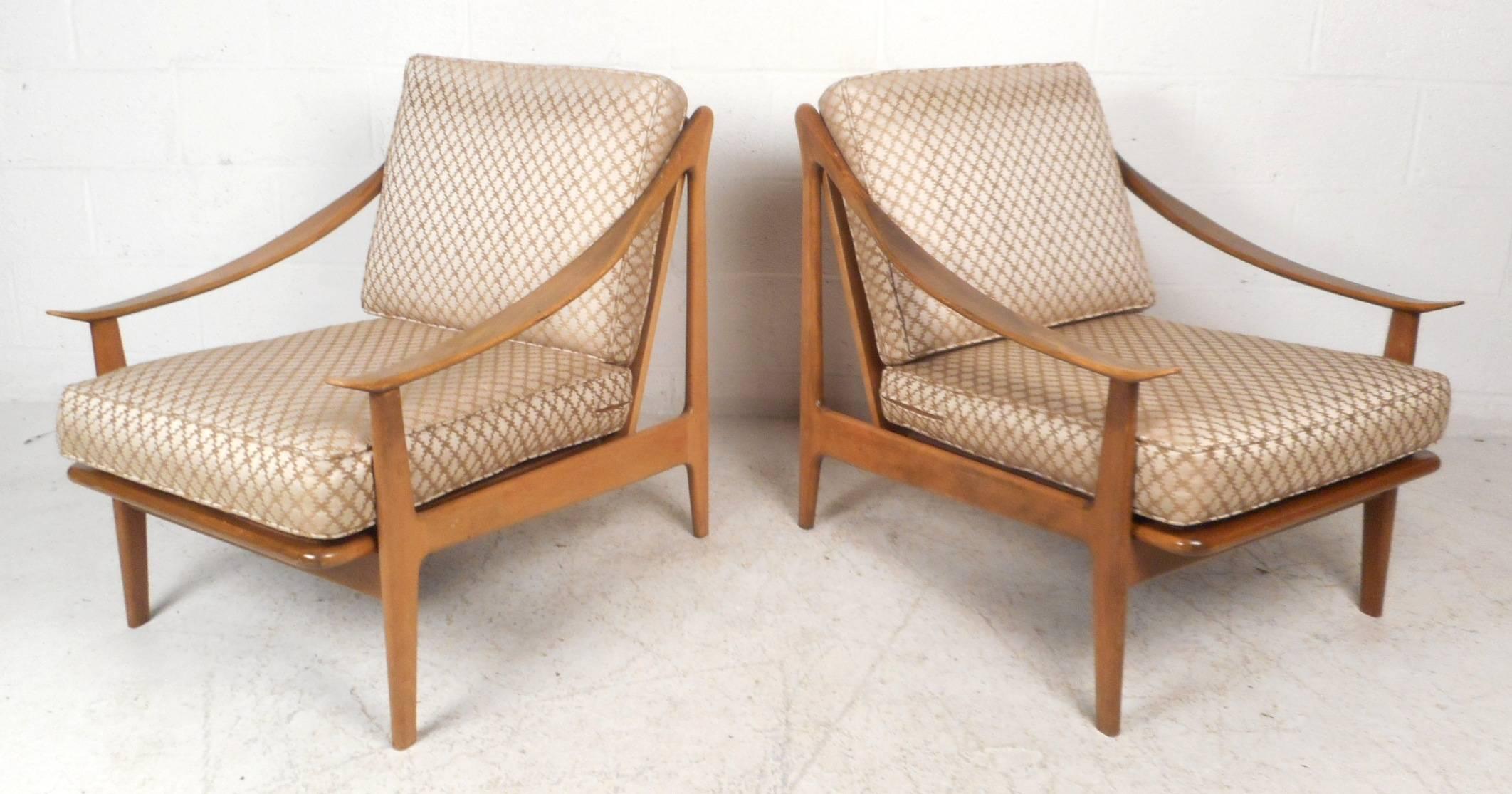 Stunning pair of vintage modern lounge chairs with unusual sculpted arm rests that abruptly slope from the backrest and arch back up at the end. Sleek design with gorgeous wood grain, a spindle backrest, and a sturdy frame. Comfortable Mid-Century