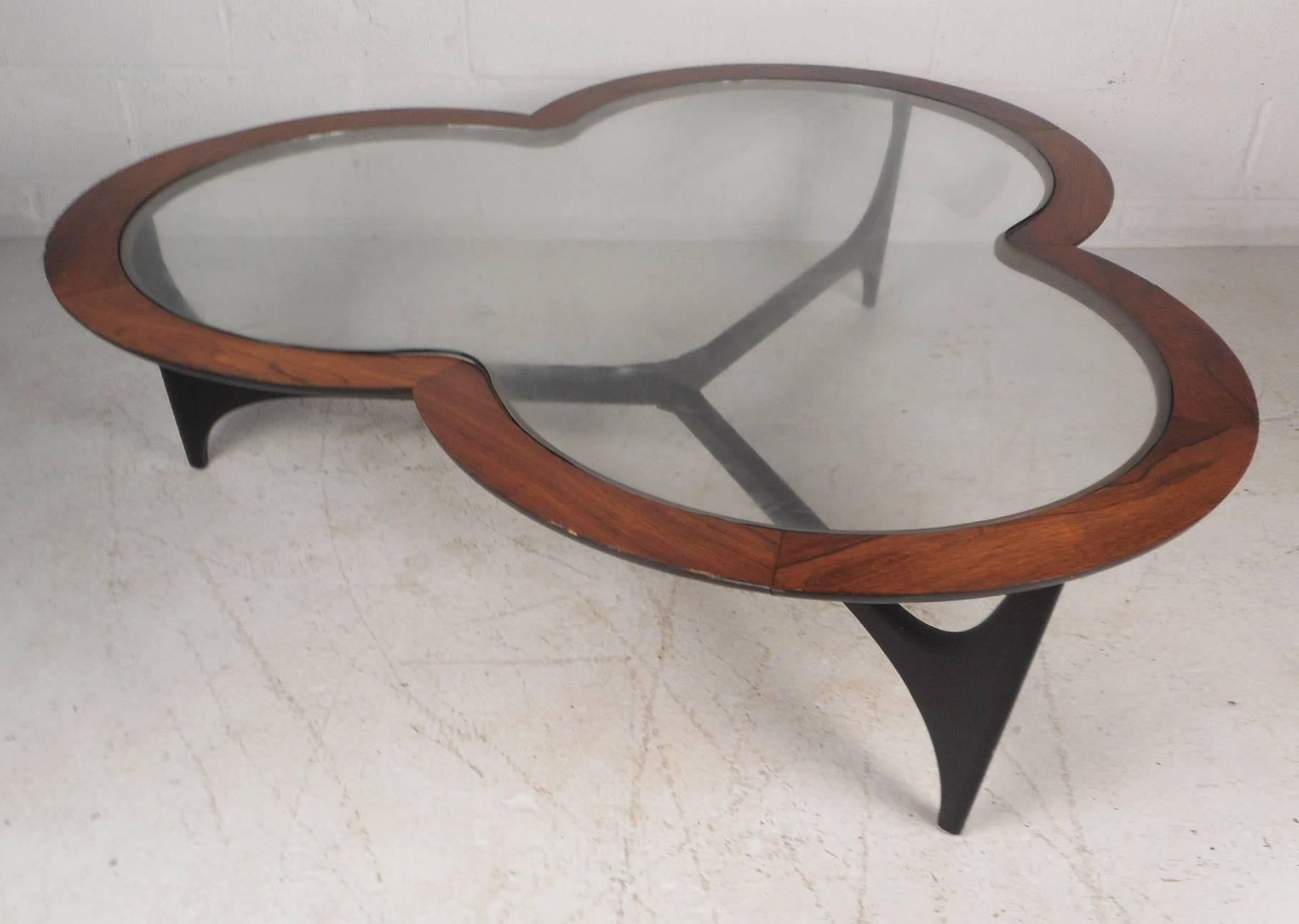 This beautiful vintage modern two-tone coffee table features a sculptural walnut frame resembling a three leaf clover with inset shaped glass on the top. The unusual ebonized base has three sturdy legs with stretchers running in between each.