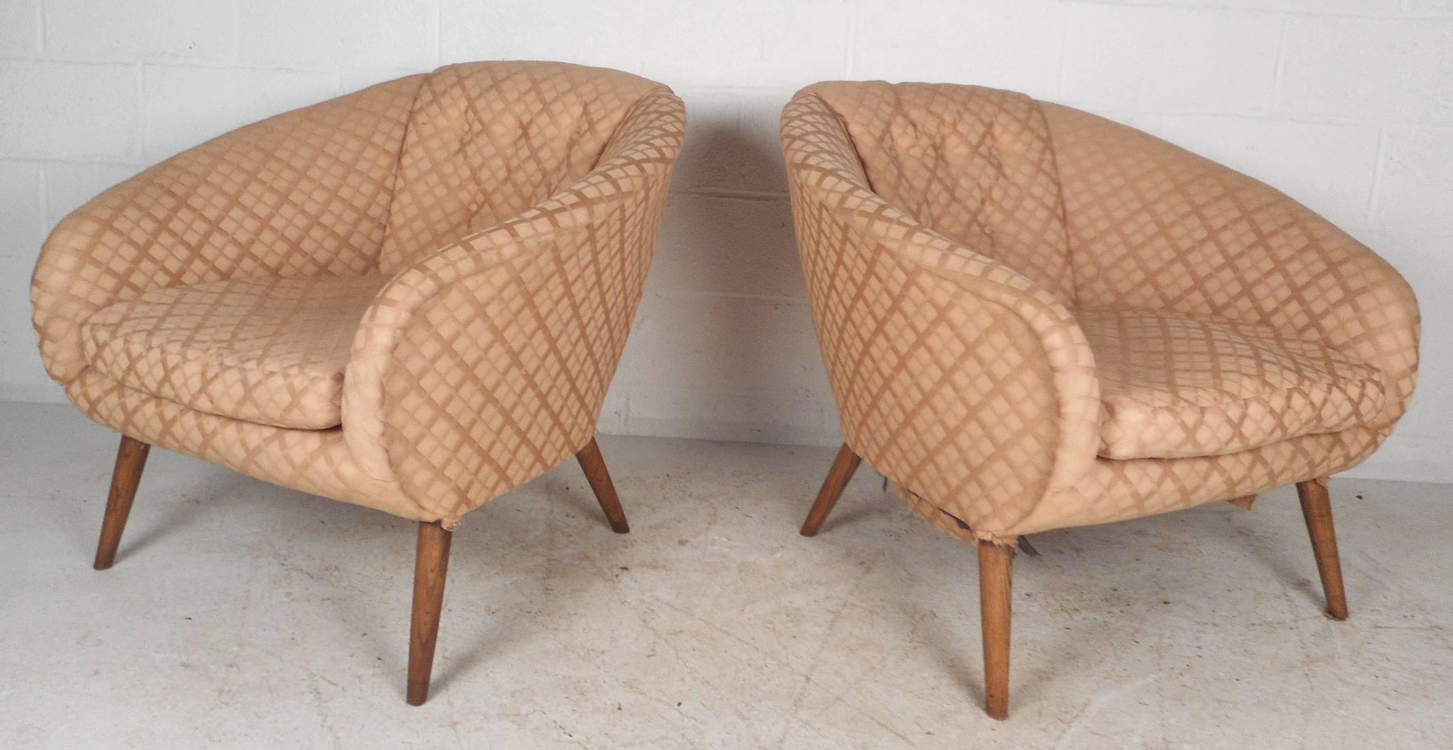 Stunning pair of vintage modern lounge chairs with a barrel backrest and tufted upholstery. Sleek design with thick padded seating, a removable cushion, and plush colorful fabric. Unique tapered and splayed walnut legs add to the Mid-Century appeal.