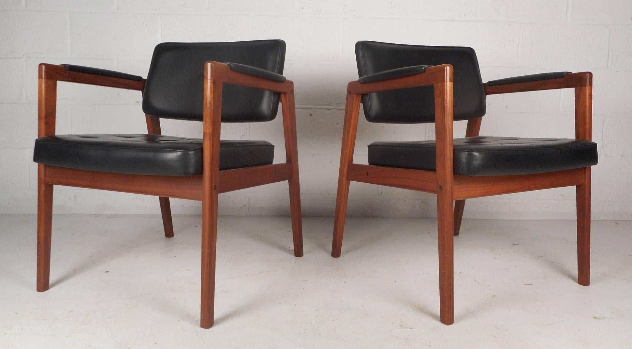 Stunning pair of vintage modern Swedish side chairs with tufted leather upholstery and a solid walnut frame. Unique design features upholstered arm rests and thick padded seating ensuring maximum comfort. Sleek Mid-Century chairs with unusual