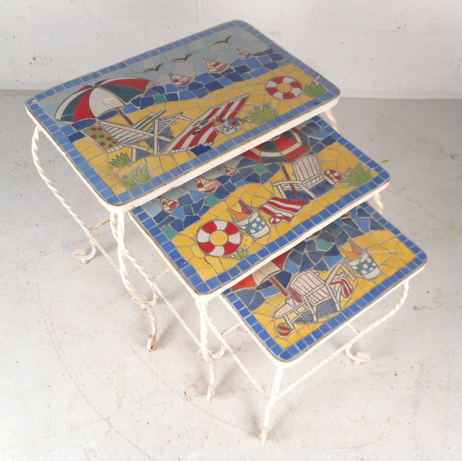 Beautiful Mid-Century Modern nesting tables with an elaborate colorful tile top displaying a fun day at the beach. Unique set features the ability to sit comfortably on top of one another for easy storage. Gorgeous imagery and heavy iron bases add