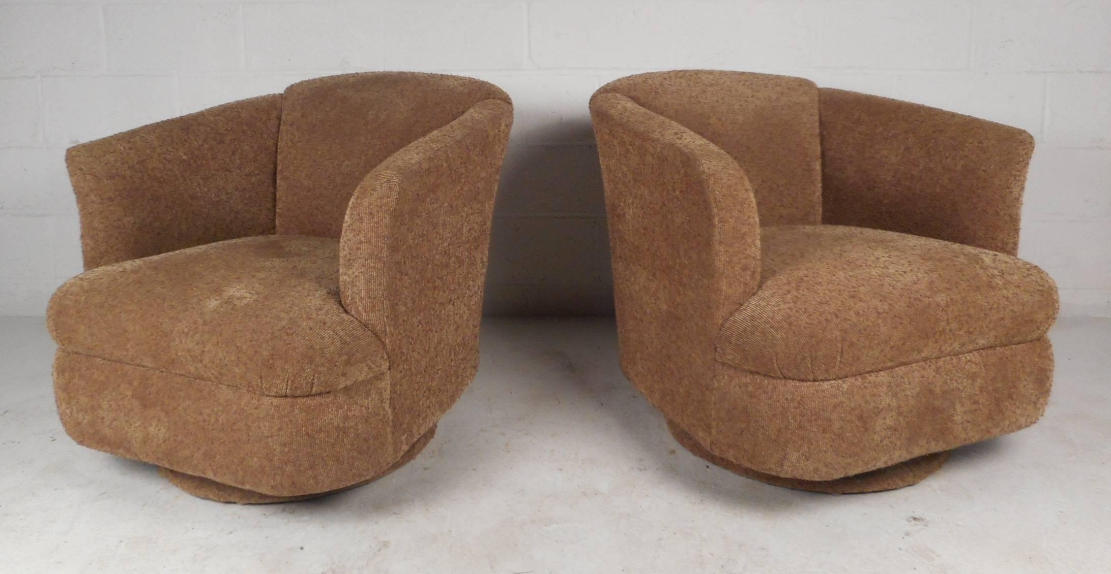 This stunning pair of vintage modern lounge chairs feature a barrel backrest and a swivel base. Unique design entirely covered in plush beige upholstery down to the base. These extremely comfortable chairs make the perfect addition to any seating