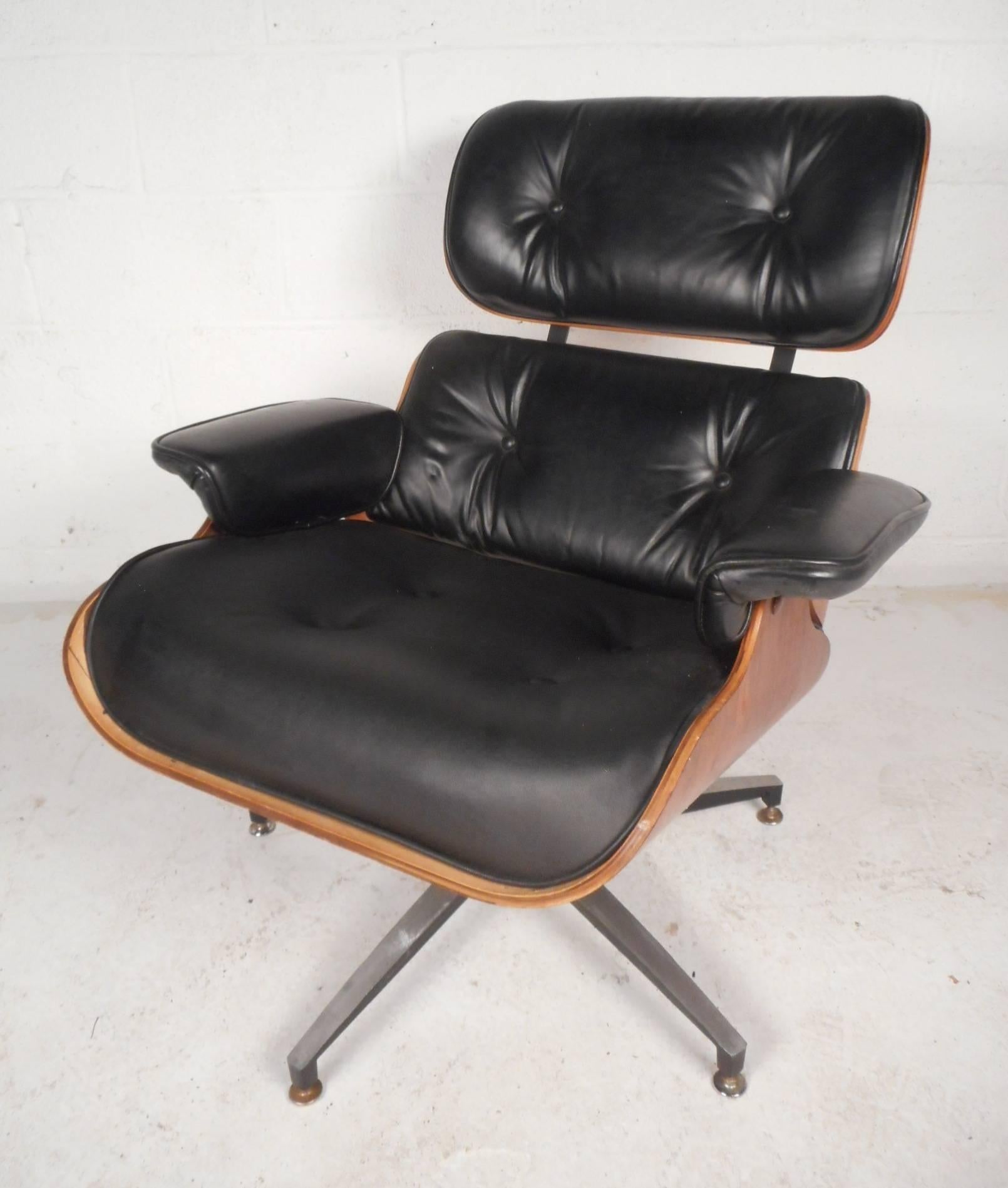 Gorgeous vintage modern lounge chair and ottoman with a hard shell walnut frame. Sleek design is upholstered in black tufted vinyl with a metal swivel/tilt base. Comfortable and stylish seating has the perfect contours for the body with unusual