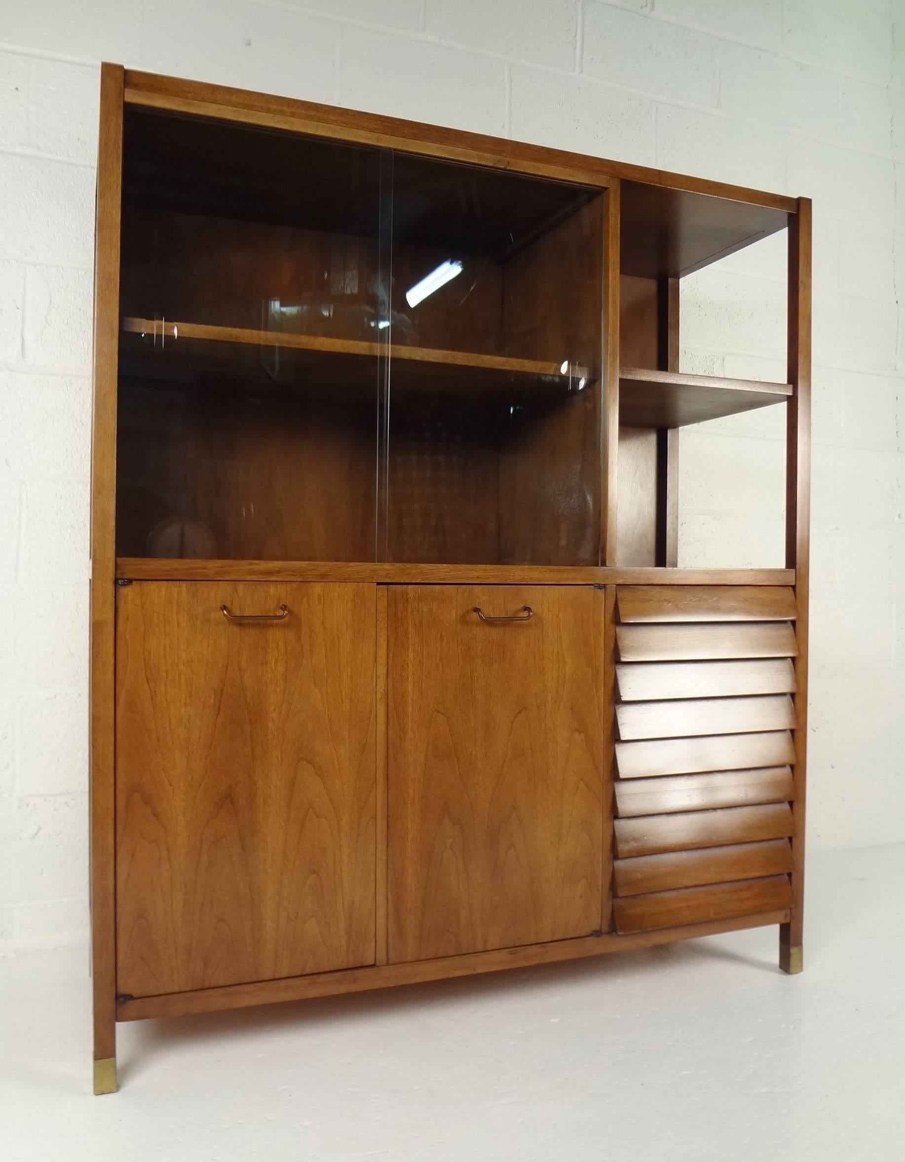 This elegant vintage modern hutch features plenty of room for storage and displaying items. Sleek design has a large compartment on top with a shelf and sliding glass doors in front. Unique design has an open display area on the left side with two