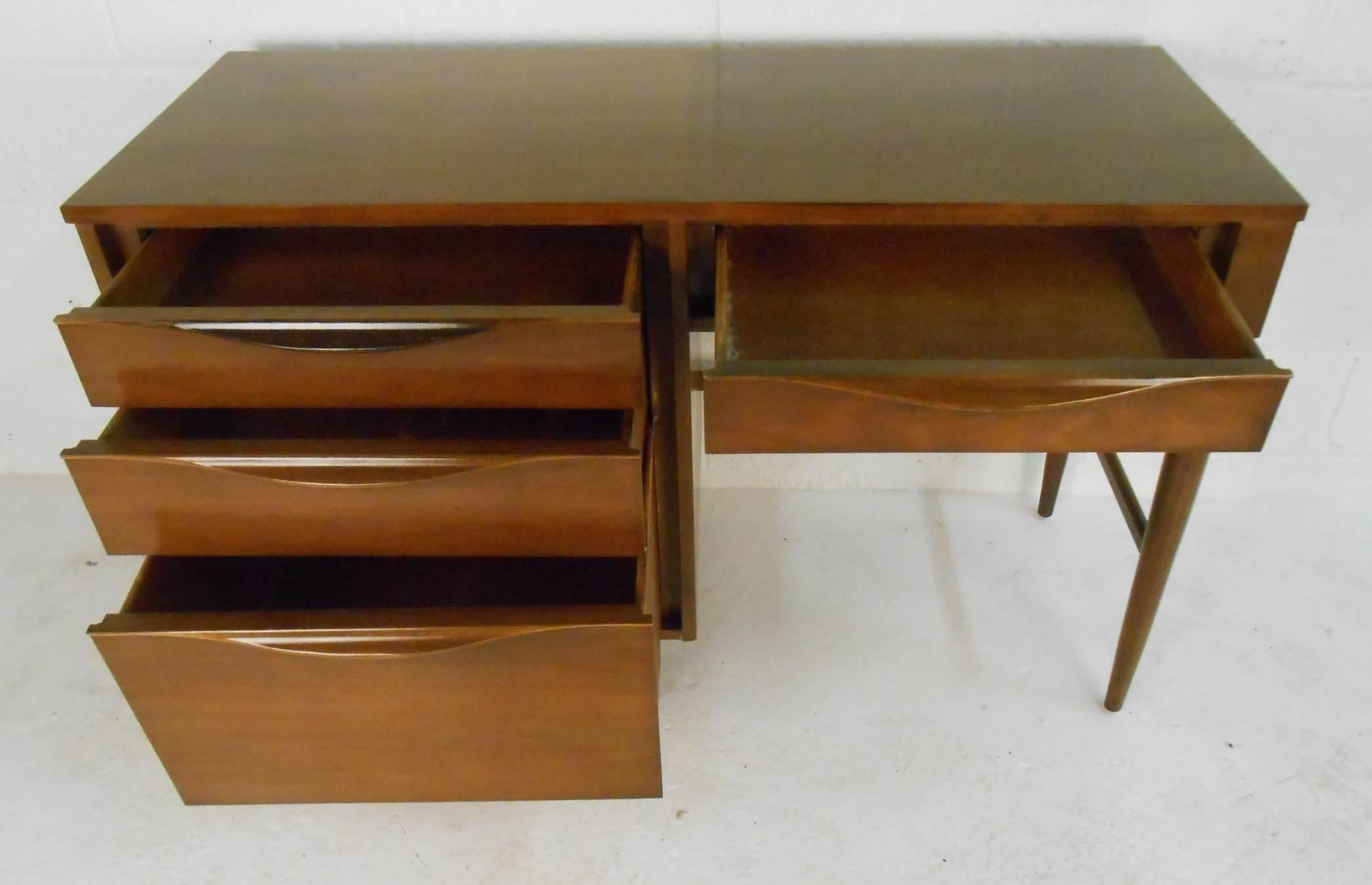 This beautiful vintage modern desk features unique curved drawer pulls and a finished back. Sleek design with a 48 inch wide top providing plenty of work space and four large drawers for ample storage space. Quality craftsmanship with an elegant