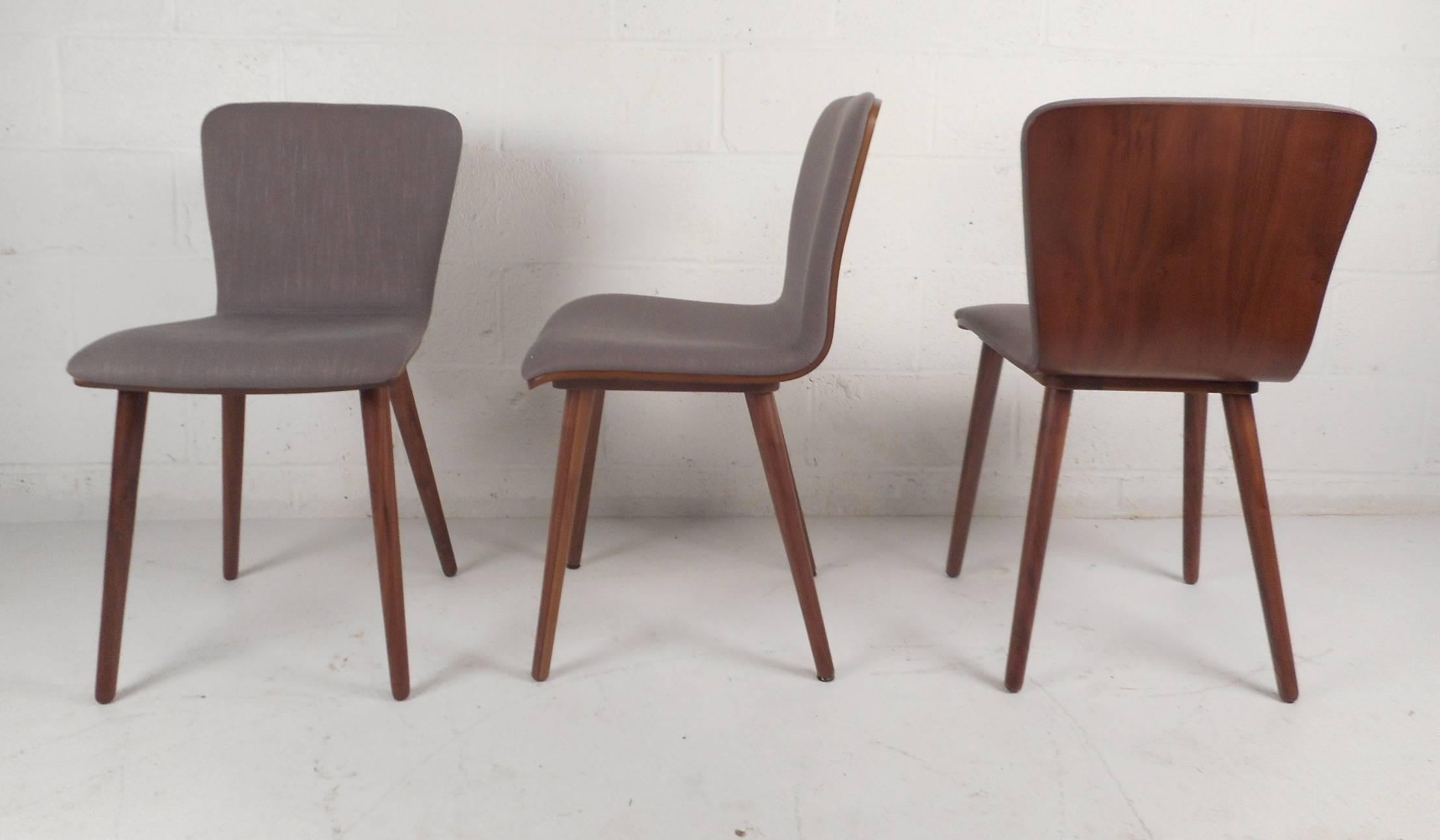 This stunning set of six Mid-Century Modern style dining chairs feature upholstered seating with a wood backing. Stylish two-tone slipper design perfectly contours to the body ensuring maximum comfort. Unique chairs with beautiful wood grain and