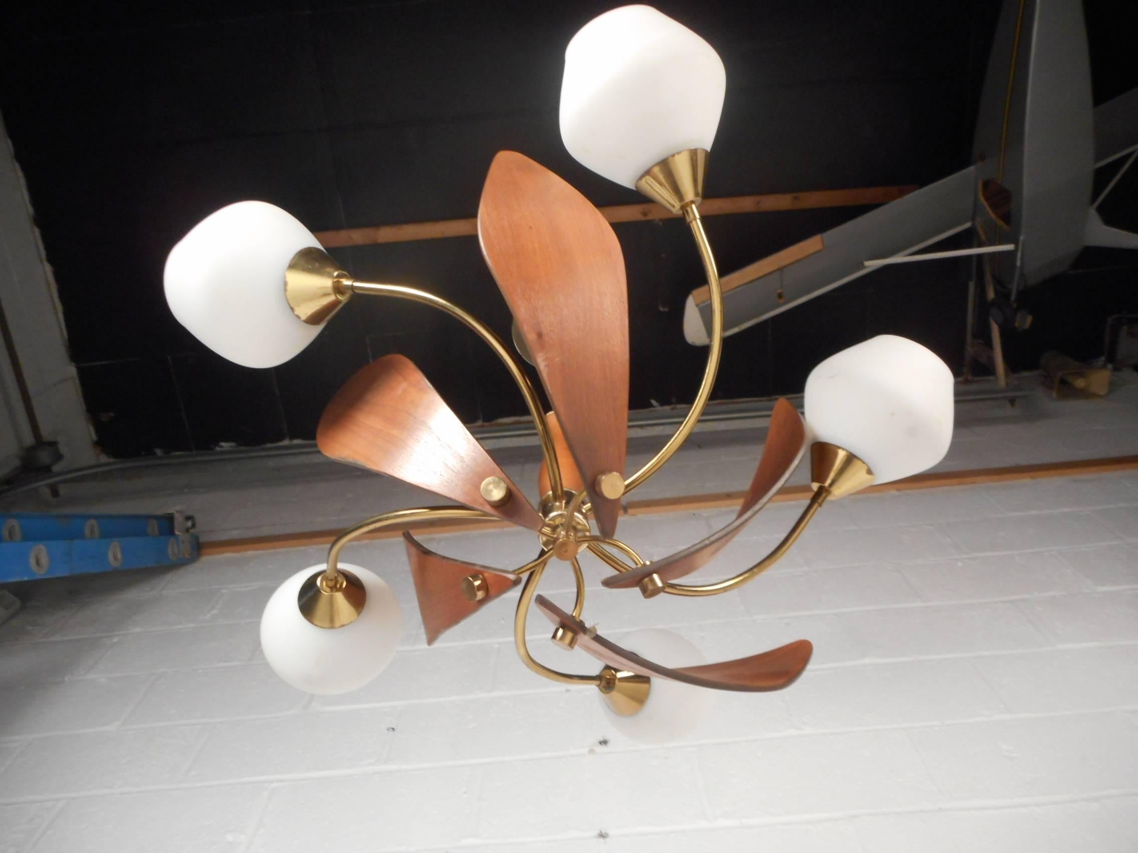This stunning vintage modern hanging lamp features sculpted teak wood and lovely white globes over each fixture. Quality design with bent brass rods running to each fixture. Elegant Mid-Century piece looks incredible when light bounces off of the