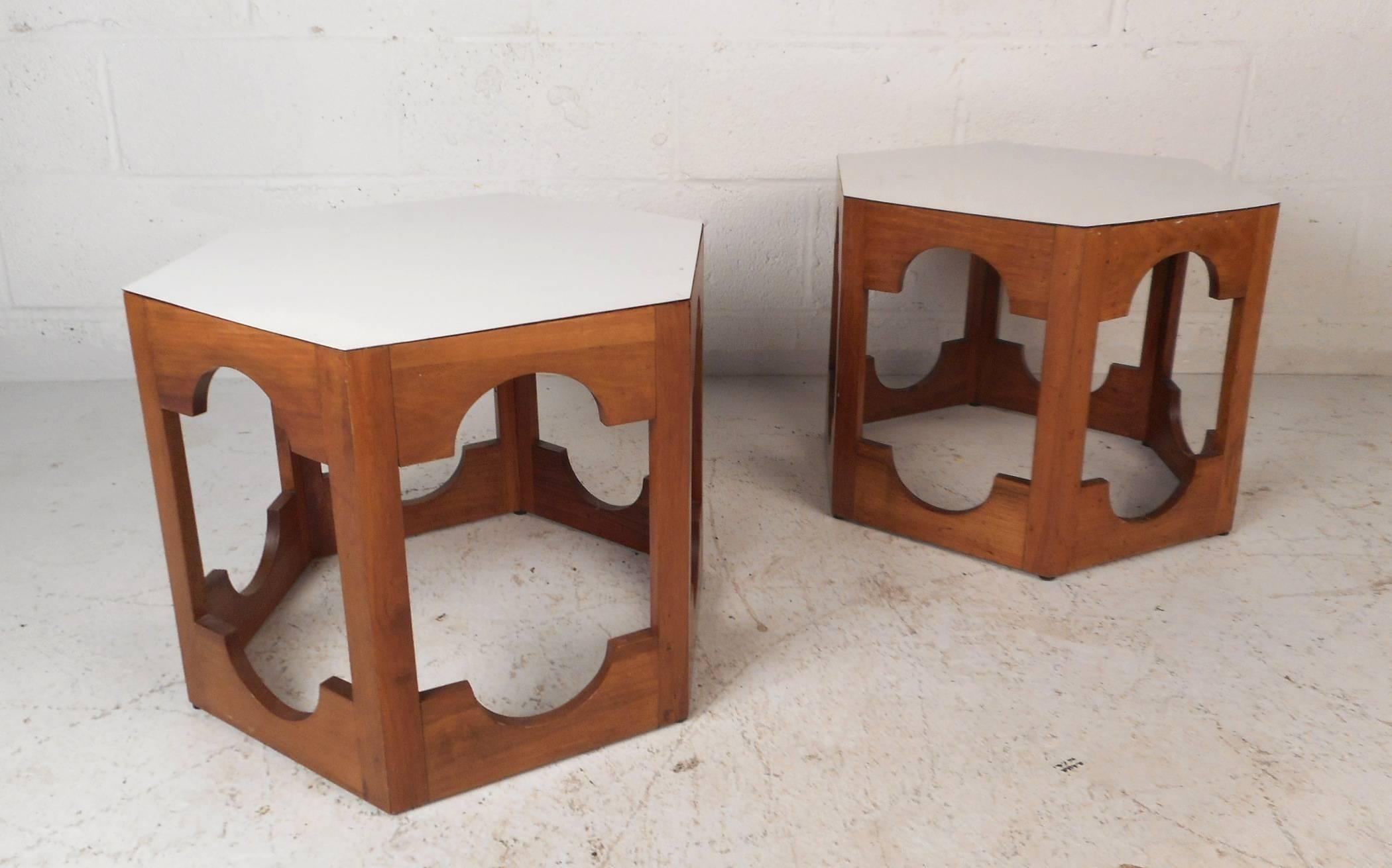 This beautiful pair of vintage modern end tables feature a white laminate top and a walnut base. Sleek design with unusual cut-out designs on all sides and a hexagonal shape. Versatile midcentury pieces function as pedestals, end tables, or simply a
