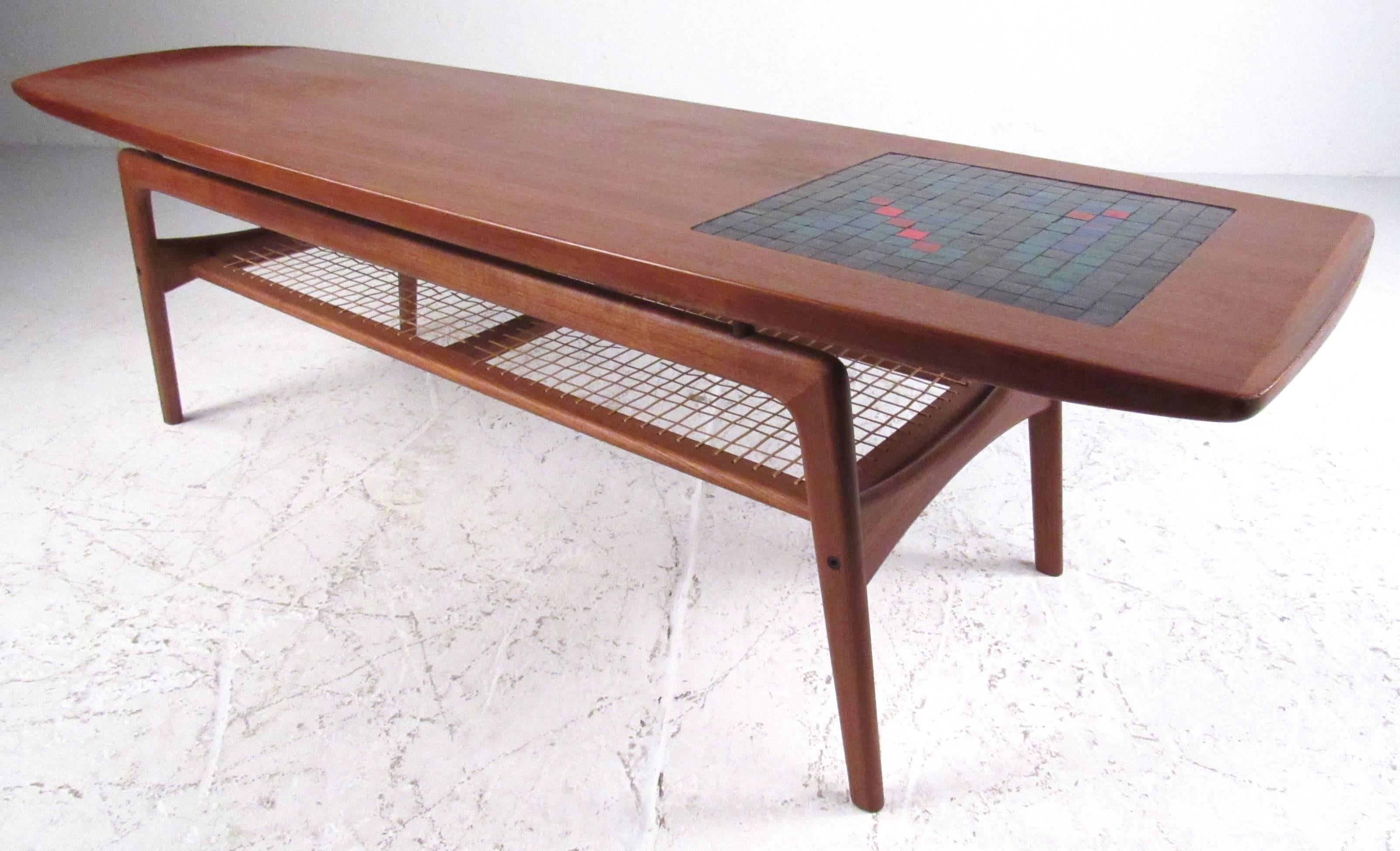 Elegant, sculptural, Danish modern coffee table designed by Arne Hovmand-Olsen and produced by Mogens Koch, circa 1960s. Colorful mosaic inlay on top with caned lower magazine shelf. Danish Furniture Makers Control label. Please confirm item