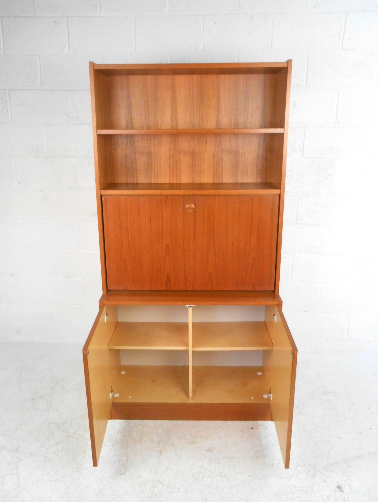 This beautiful vintage modern secretary features a drop front desk that hides a compartment with a white laminate interior. Versatile design functions as a work desk, display cabinet, or a book shelf. This wonderful case piece offers plenty of room