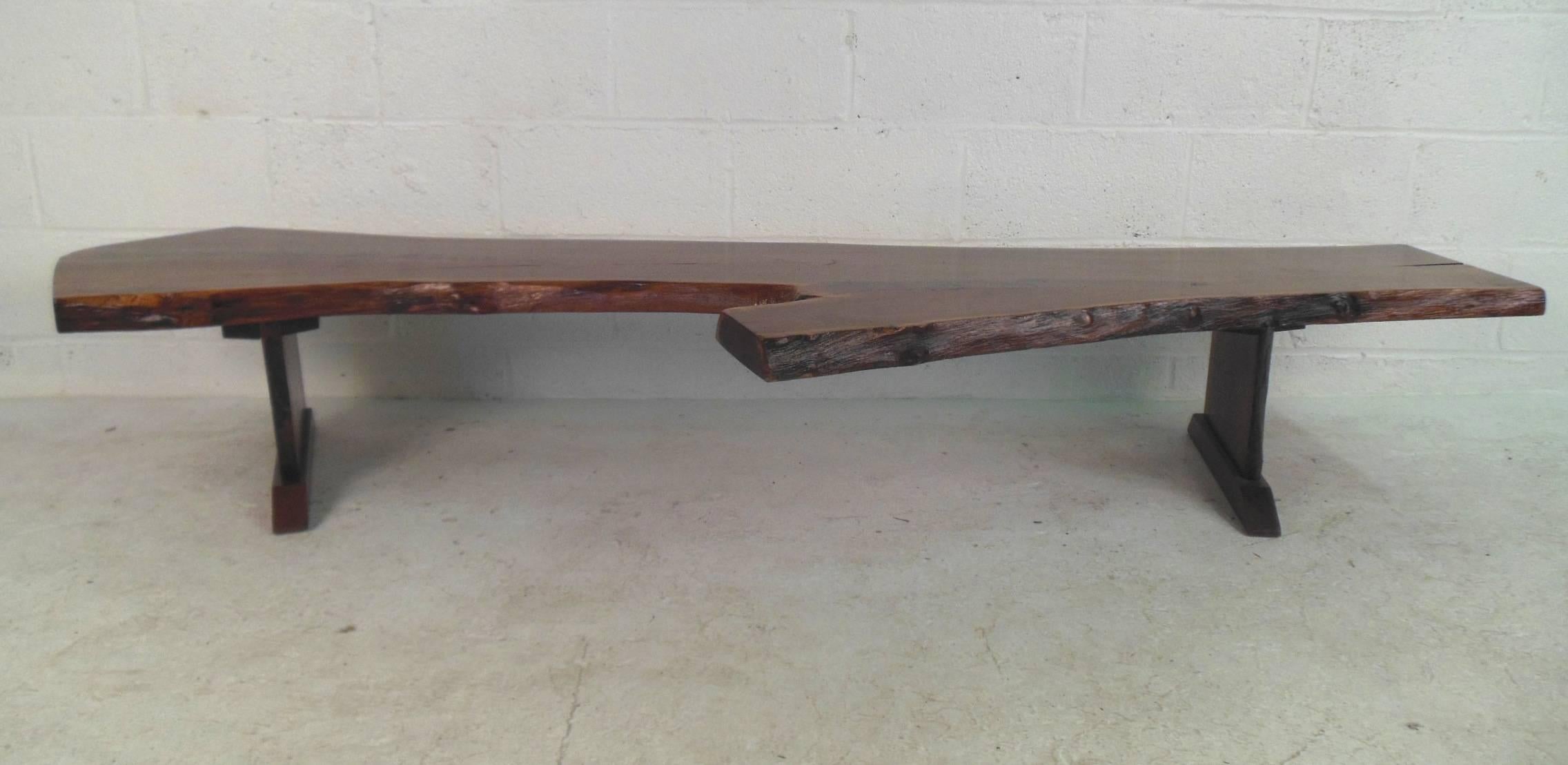 This gorgeous vintage modern coffee table features a unique live edge tree slab top with two sturdy legs. This functional piece has a large top with an unusual shape and elegant wood grain throughout. This wonderful midcentury piece makes the