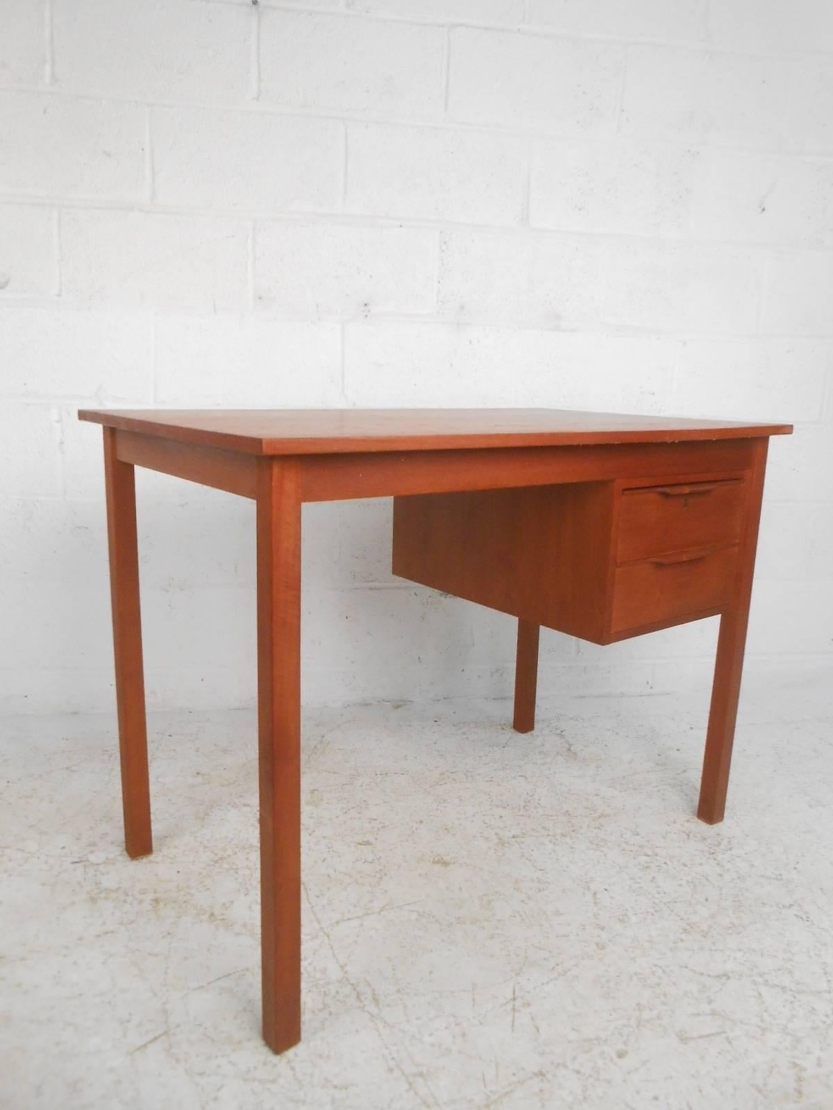 Stunning vintage modern desk features two hefty drawers with unusual sculpted pulls. Sleek compact design offers plenty of work space on the top and ample room for storage within its drawers. Quality craftsmanship with a finished back, long sturdy