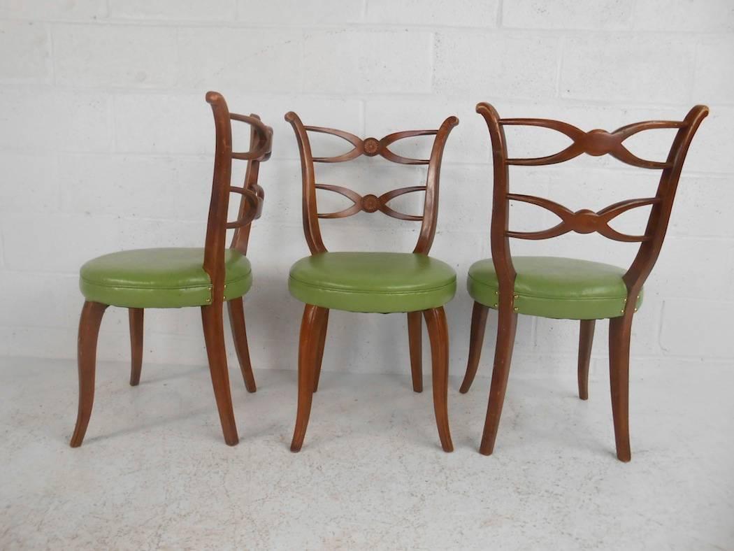 This elegant set of four vintage modern dining chairs feature a unique sculpted backrest with wonderful circular designs in the centre. Sleek design with thick padded seating covered in elaborate green vinyl. This fabulous set has an incredible