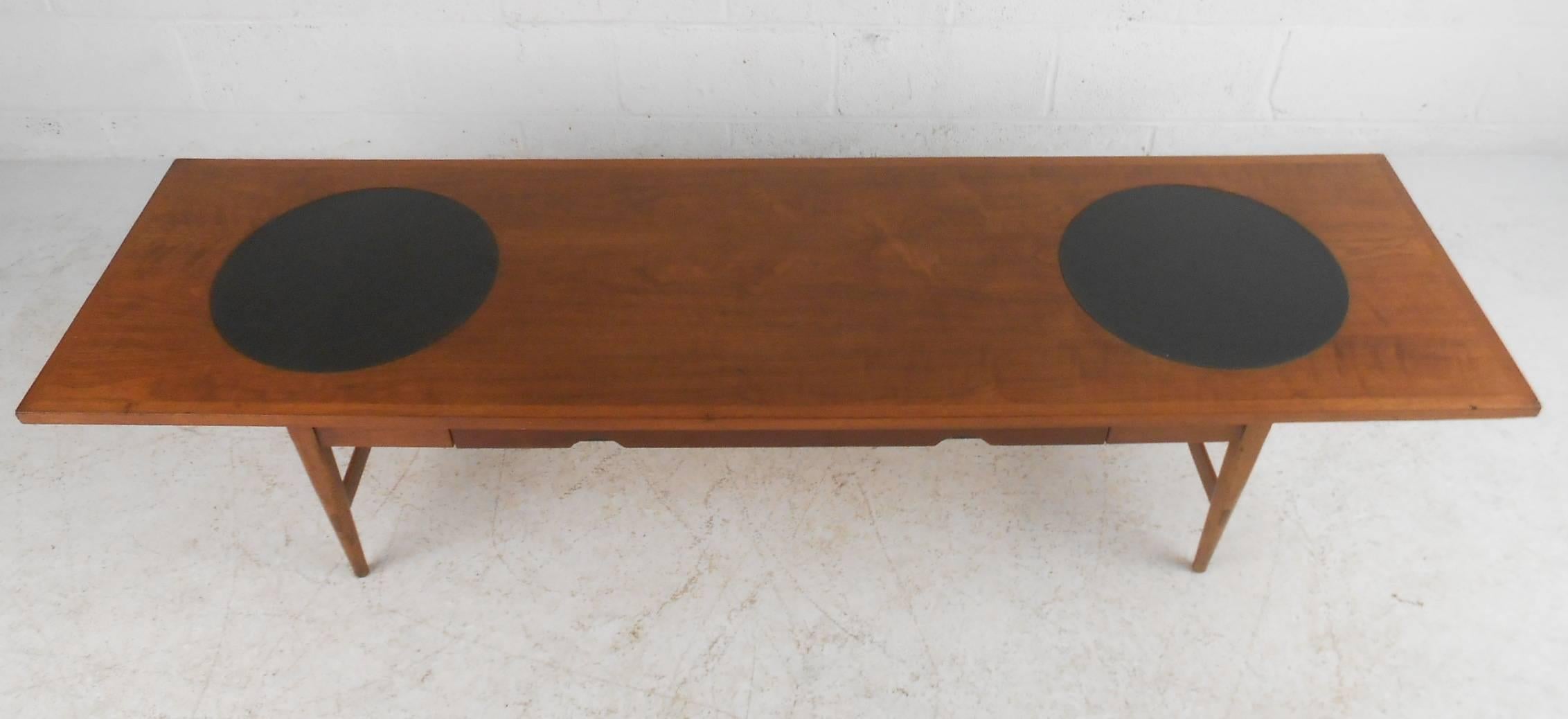 Designed by Paul McCobb for Lane's Signature Series. This gorgeous vintage modern coffee table features circular vinyl inserts on top and a hidden drawer in the front. Sleek design with a tapered legs and stretchers on each side for added