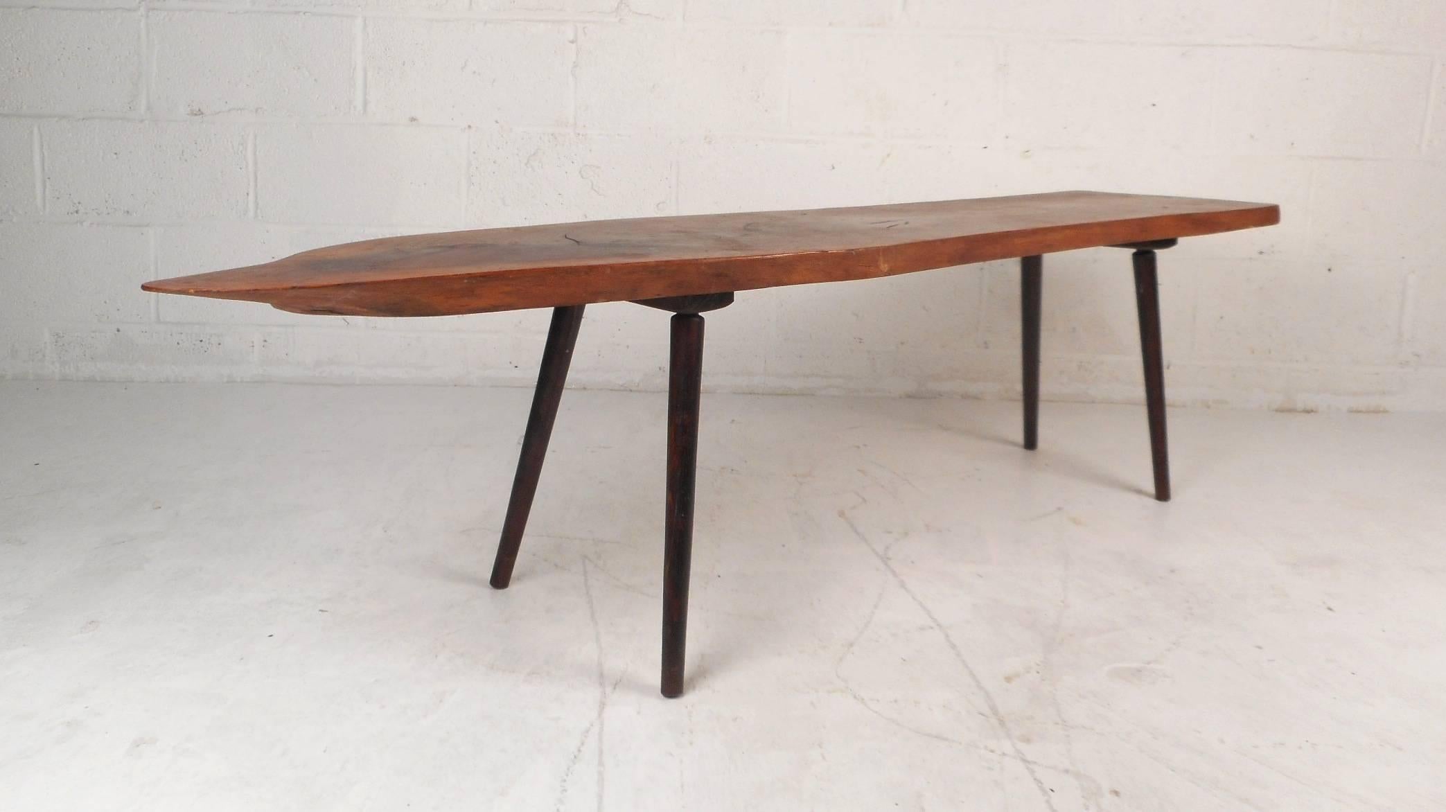 This gorgeous vintage modern coffee table features a unique tree slab top. Stylish design with splayed legs and a free-form live edge tabletop. Quality design with wonderful wood grain makes the perfect eye-catching addition to any modern interior.