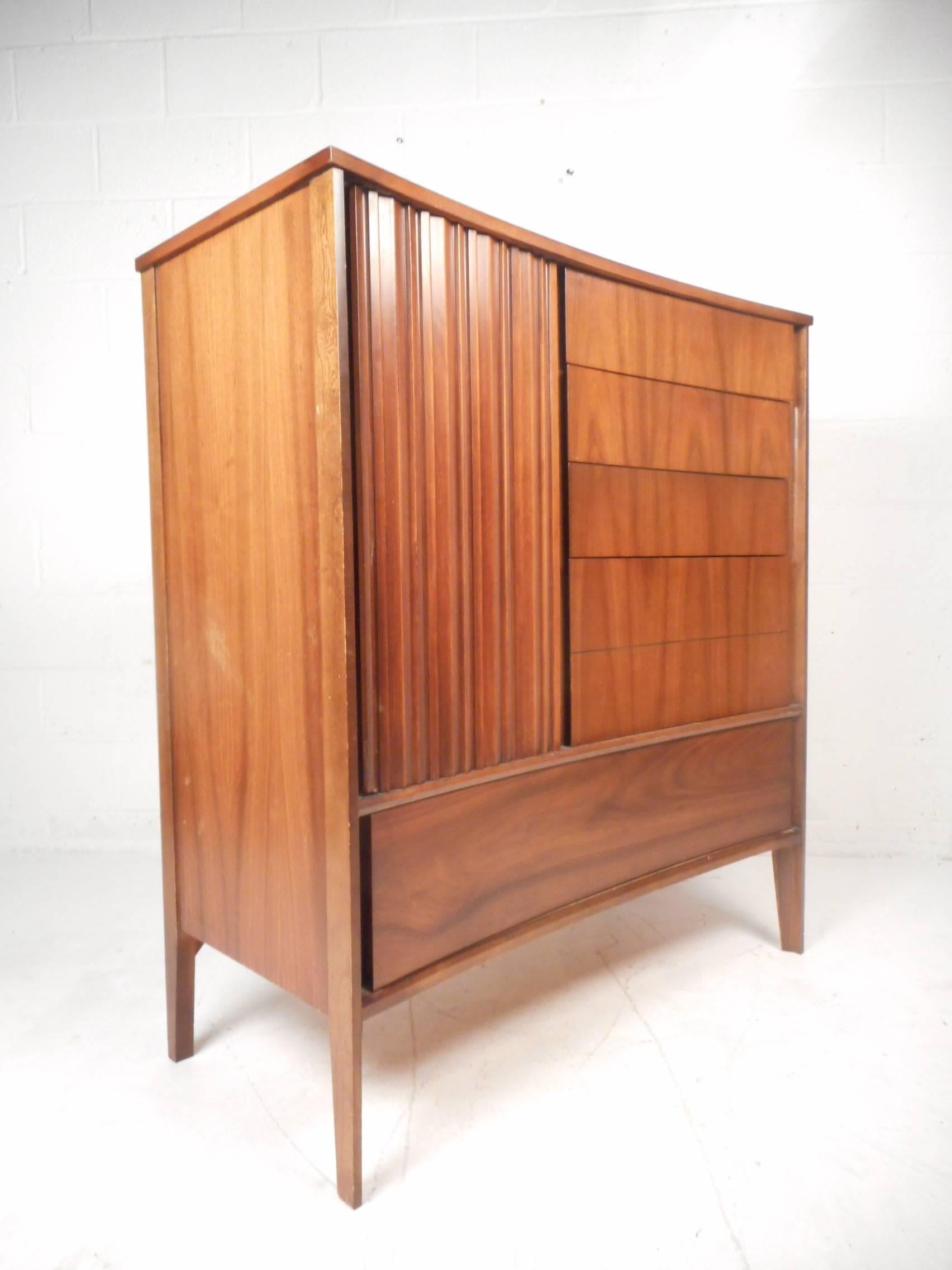 This beautiful vintage modern bedroom set includes a low dresser, a highboy, and two night stands. Sleek design features a subtle bow shaped front with lovely dark walnut wood grain. Quality craftsmanship with many wide and deep drawers offering