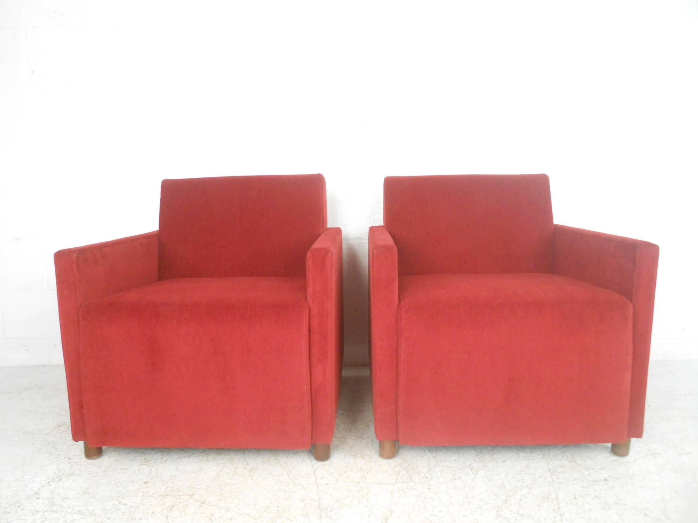 This beautiful pair of vintage modern club chairs feature plush red upholstery and sturdy walnut legs. Stylish design with thick padded seating and low arm rests. The straight line cube design makes these extremely comfortable midcentury lounge