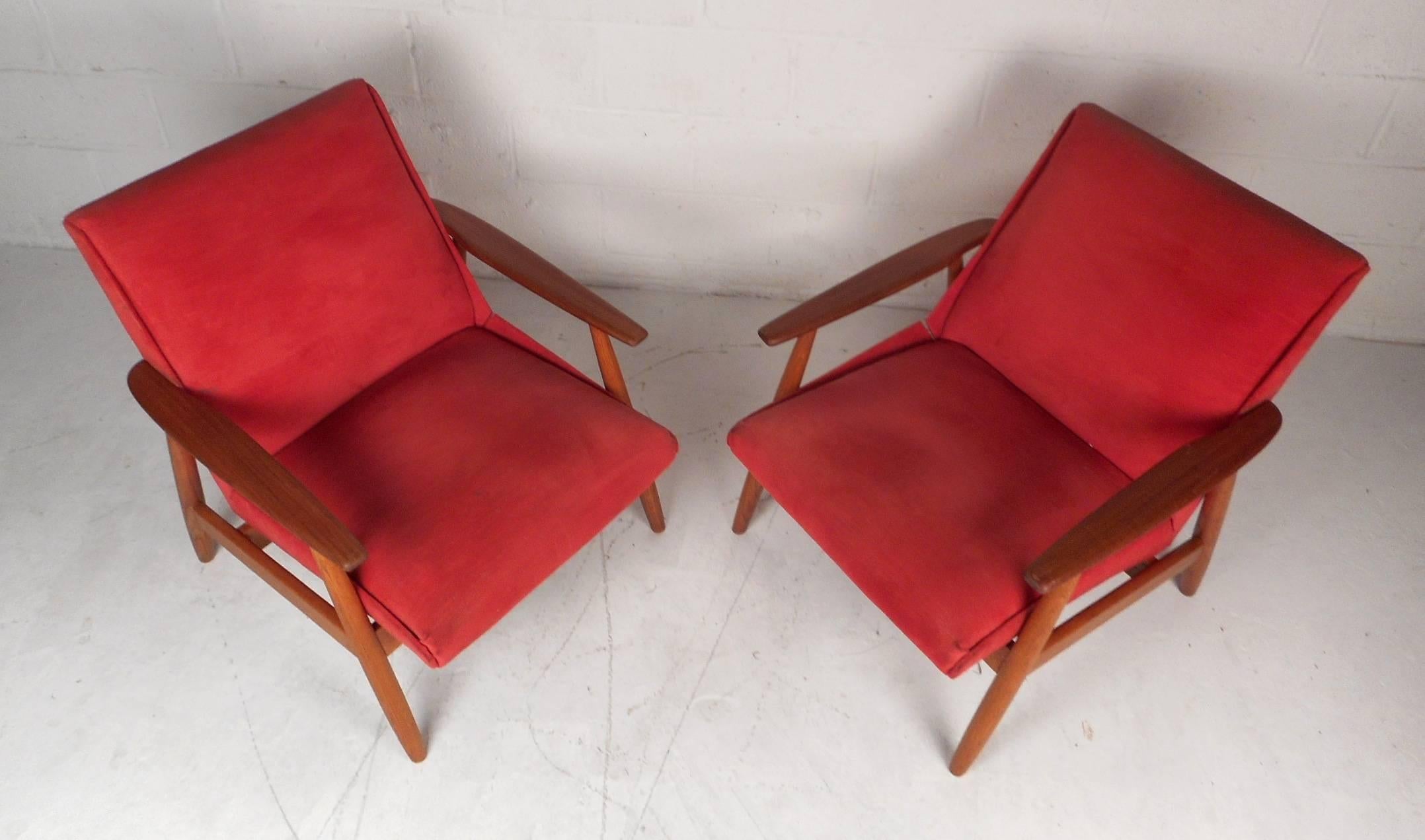 This beautiful pair of vintage modern lounge chairs feature a solid walnut frame with thick padded seating. Stylish design with angled and tapered legs adding to the midcentury appeal. This lovely pair is upholstered in plush red fabric and has