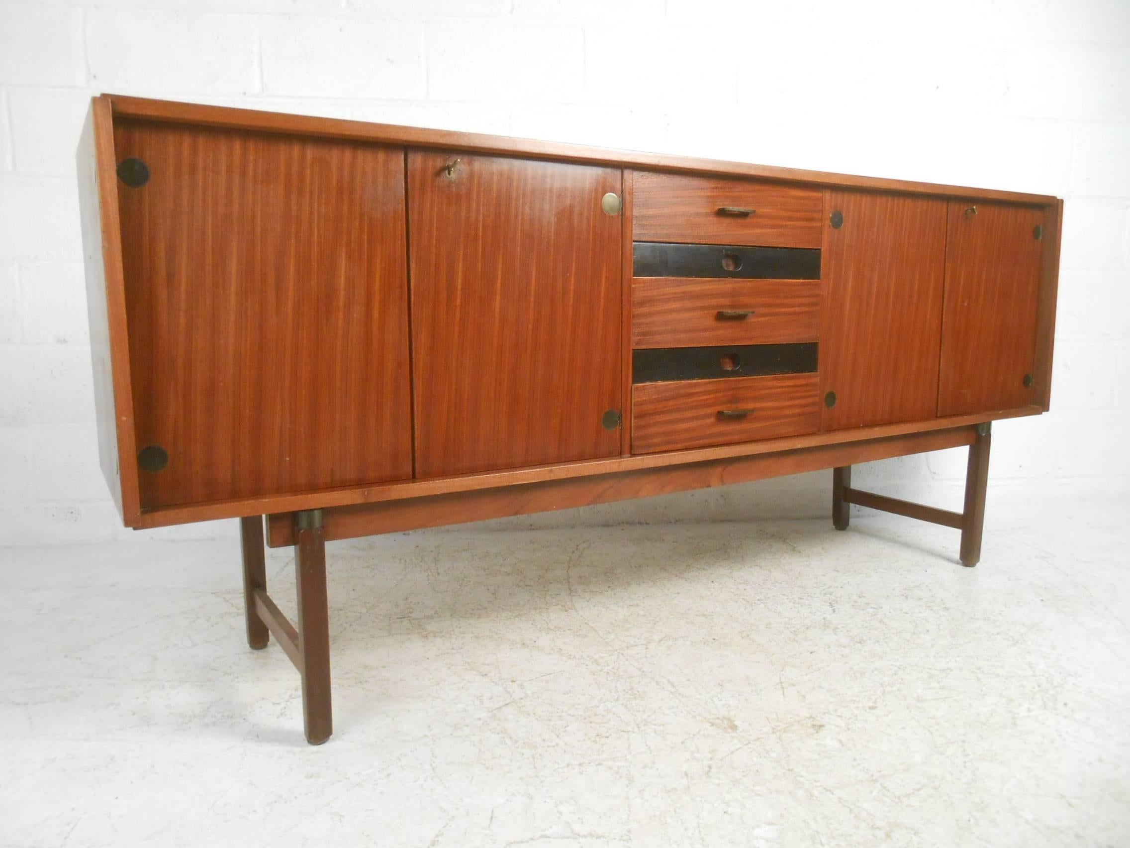 This beautiful vintage modern Italian credenza features five drawers and two separate compartments with shelves for storage. Sleek two-tone design with teak and black drawer fronts showing true quality craftsmanship. Various unusual pulls on each