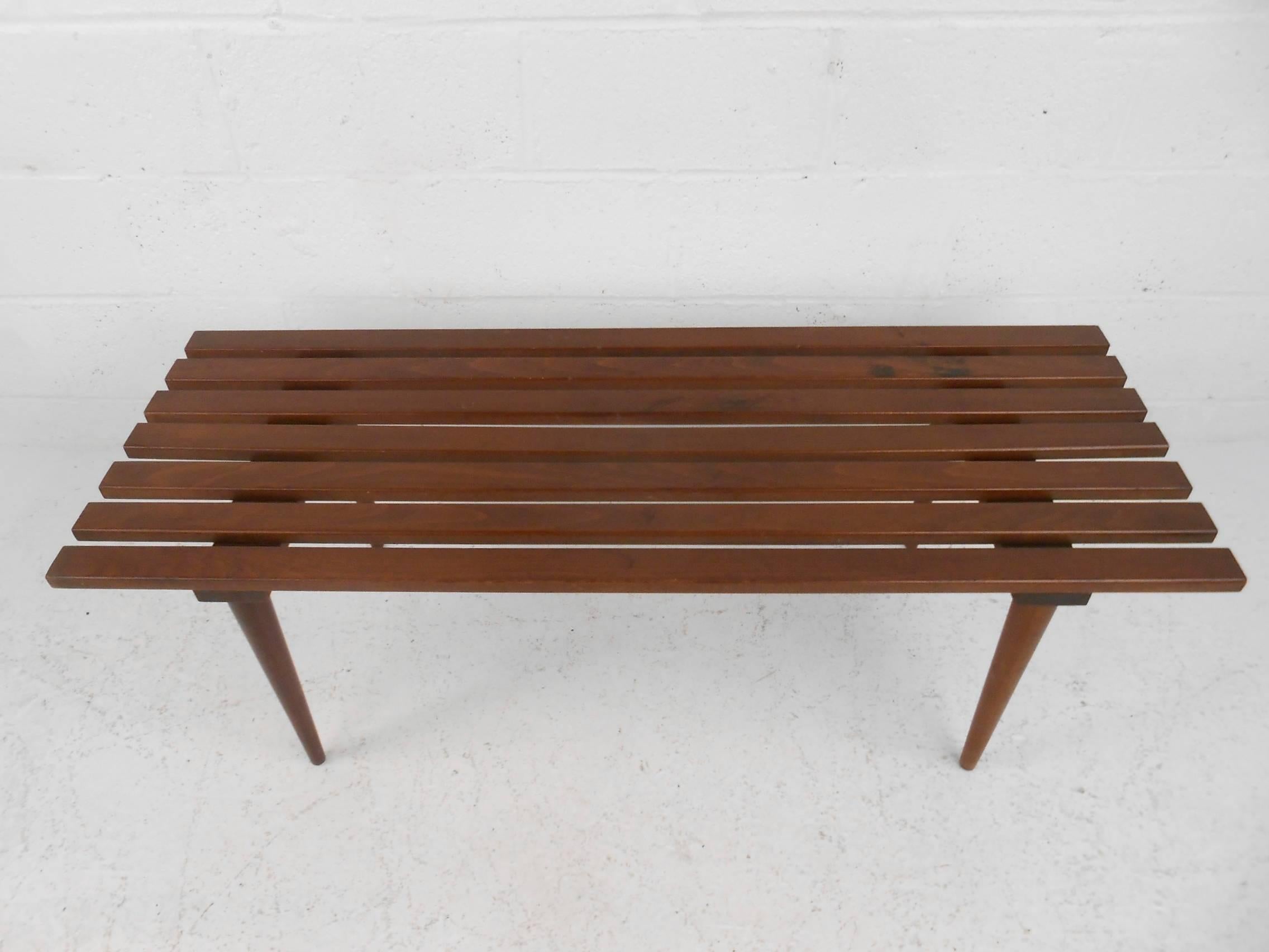 This beautiful vintage modern slat bench is made of solid walnut and features tapered legs. This unique midcentury bench makes the perfect addition to any modern interior. Please confirm item location (NY or NJ).