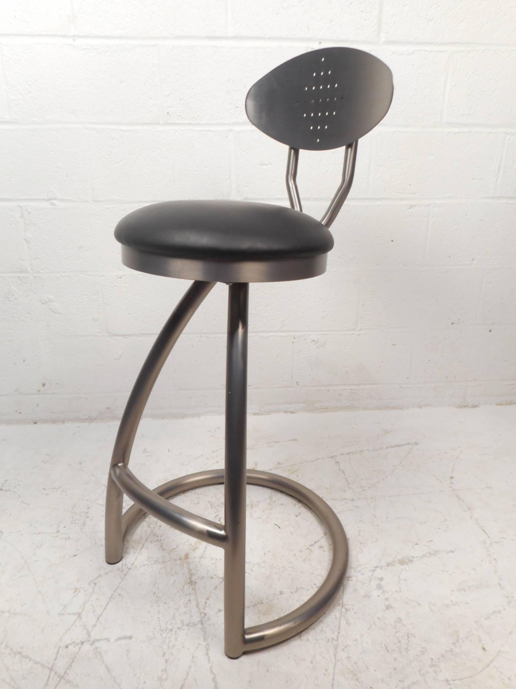 This gorgeous set of five Mid-Century Modern style bar stools feature a unique bent rod metal frame with a swivel backrest that tilts up and down. The sleek cantilever design has thick padded seating covered in black vinyl ensuring maximum comfort.