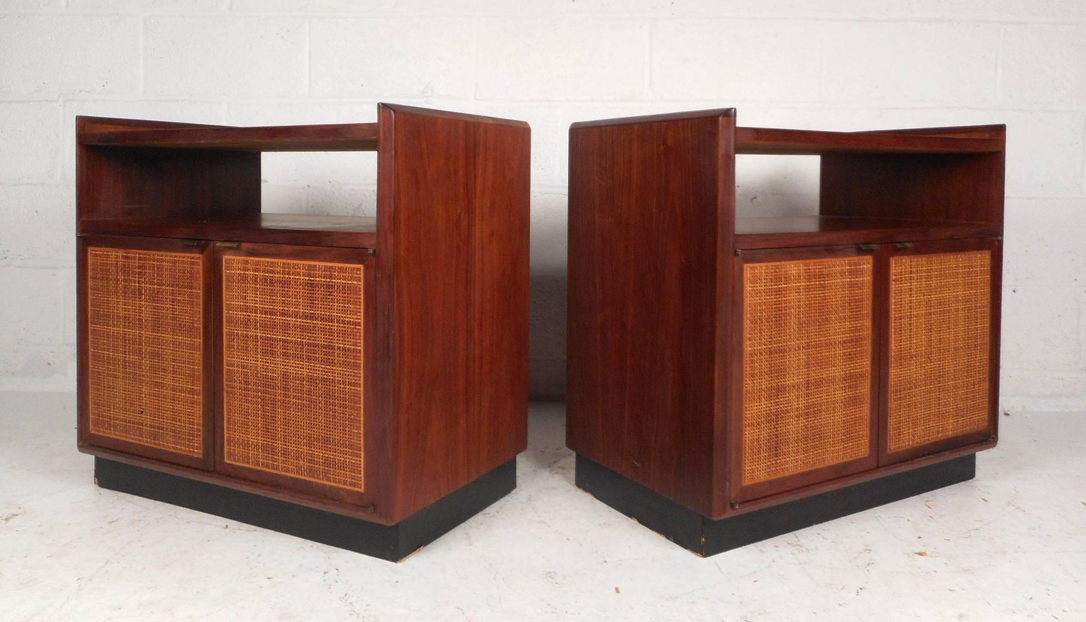 This beautiful vintage modern pair of end tables feature cane front cabinet doors that open up to unveil a large compartment for storage. Sleek design with two tiers for placing items, sculpted brass cabinet pulls, and a black painted base. Elegant
