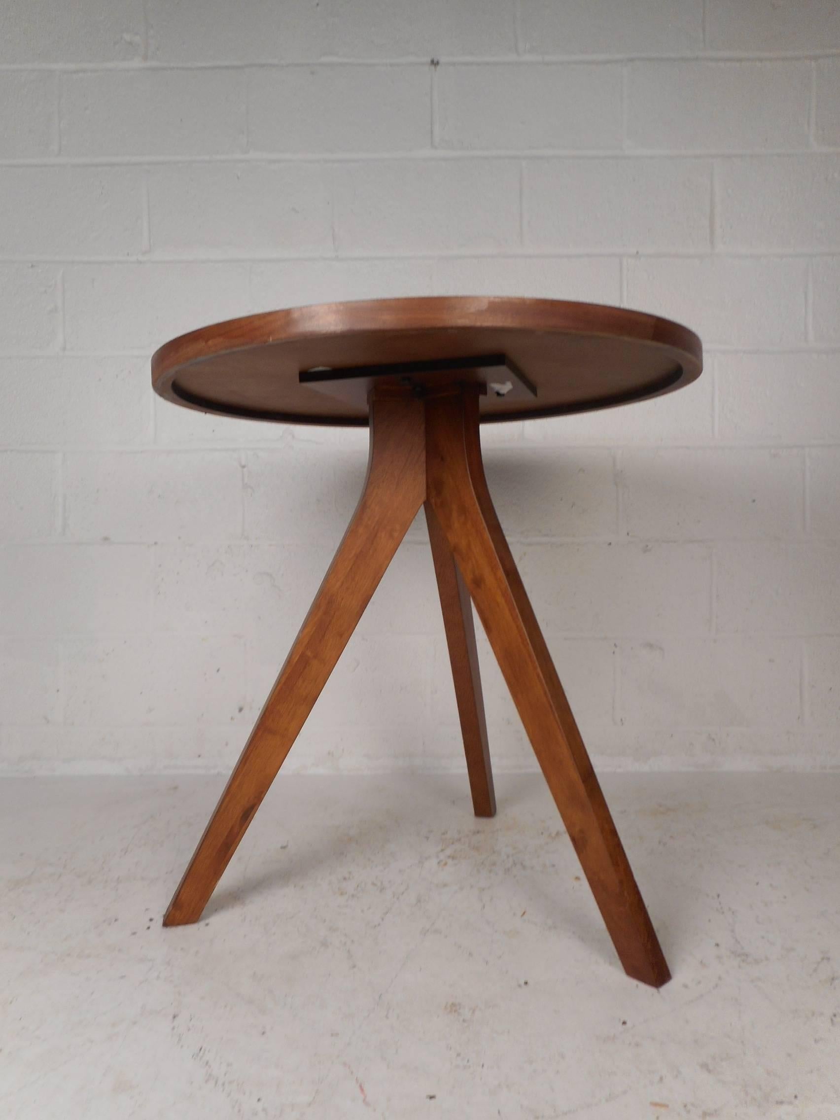 This beautiful Mid-Century Modern style kitchen table features a round top with long angled legs. Versatile design works perfectly as a pedestal, tall end table, or a game table. The sleek design has tapered and splayed legs adding to the allure.
