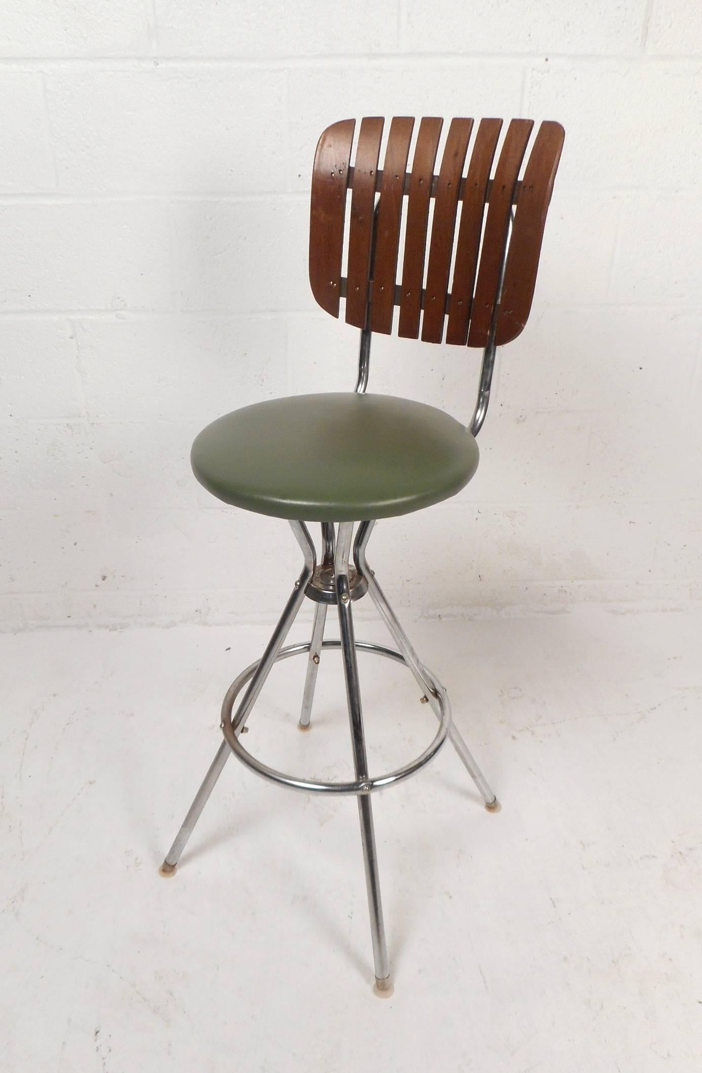 This beautiful set of four vintage modern bar stools by Arthur Umanoff feature uniquely shaped slatted back rests and wonderful green vinyl seats. Sleek design sits on top of a tubular chrome frame with unusual splayed legs. These unique bar stools