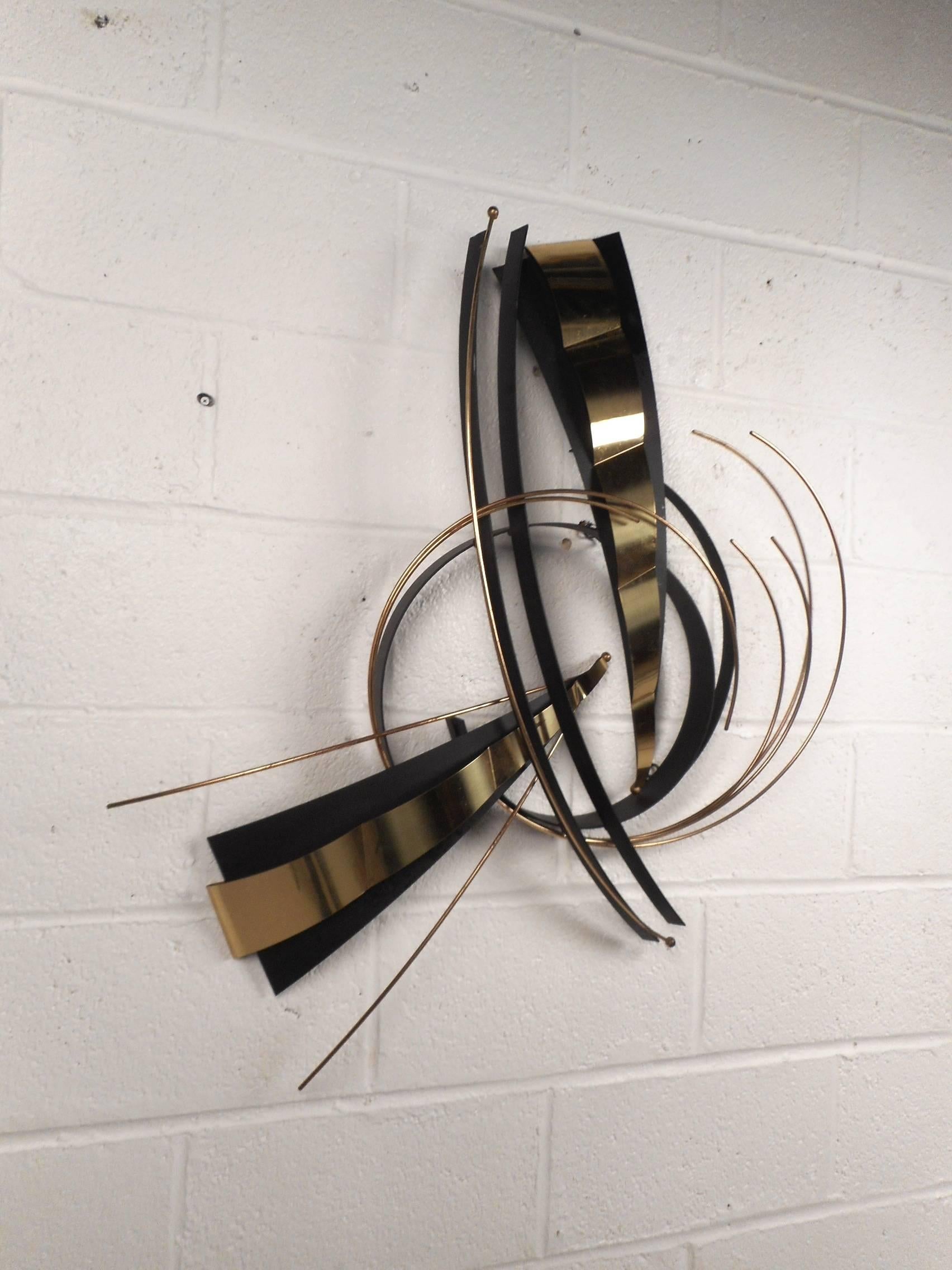 This beautiful Mid-Century Modern wall art is made of metal. Two-tone design with gold and black colored metals. Elegant piece with various shapes and sizes running in different directions adding to the allure. This fabulous vintage modern wall art