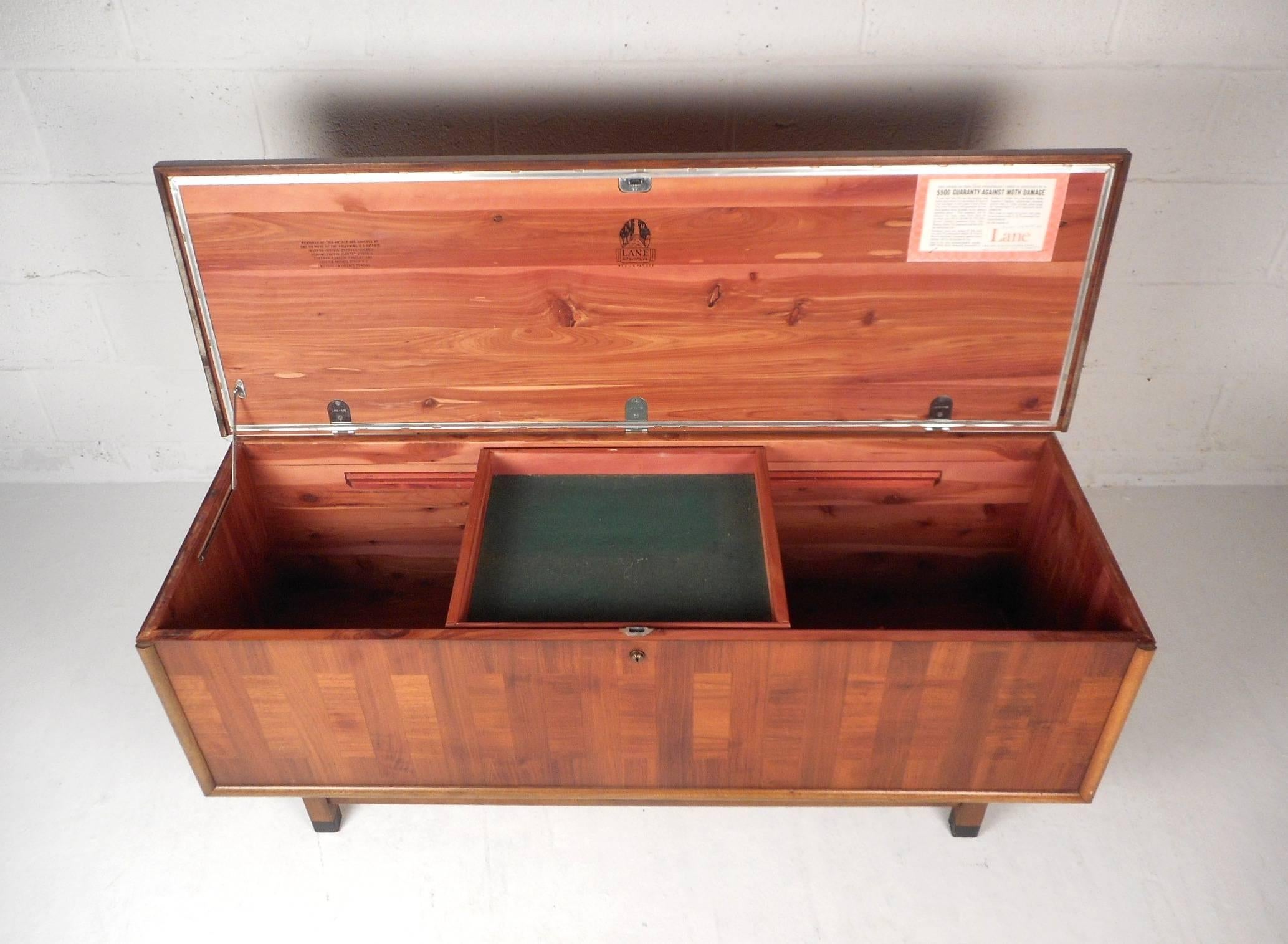 This beautiful vintage modern cedar chest opens up to unveil a sliding removable shelf and a large storage compartment. Stunning walnut wood grain with lovely oak trim around the front adding to the allure. This stylish case piece opens up with a
