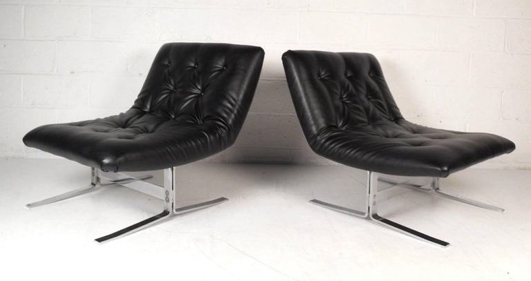 This gorgeous vintage modern pair of lounge chairs have sleek black leather upholstery with tufted buttons. The wide slipper design with overstuffed seating provides maximum comfort without sacrificing style. The heavy flat bar chrome sled legs and